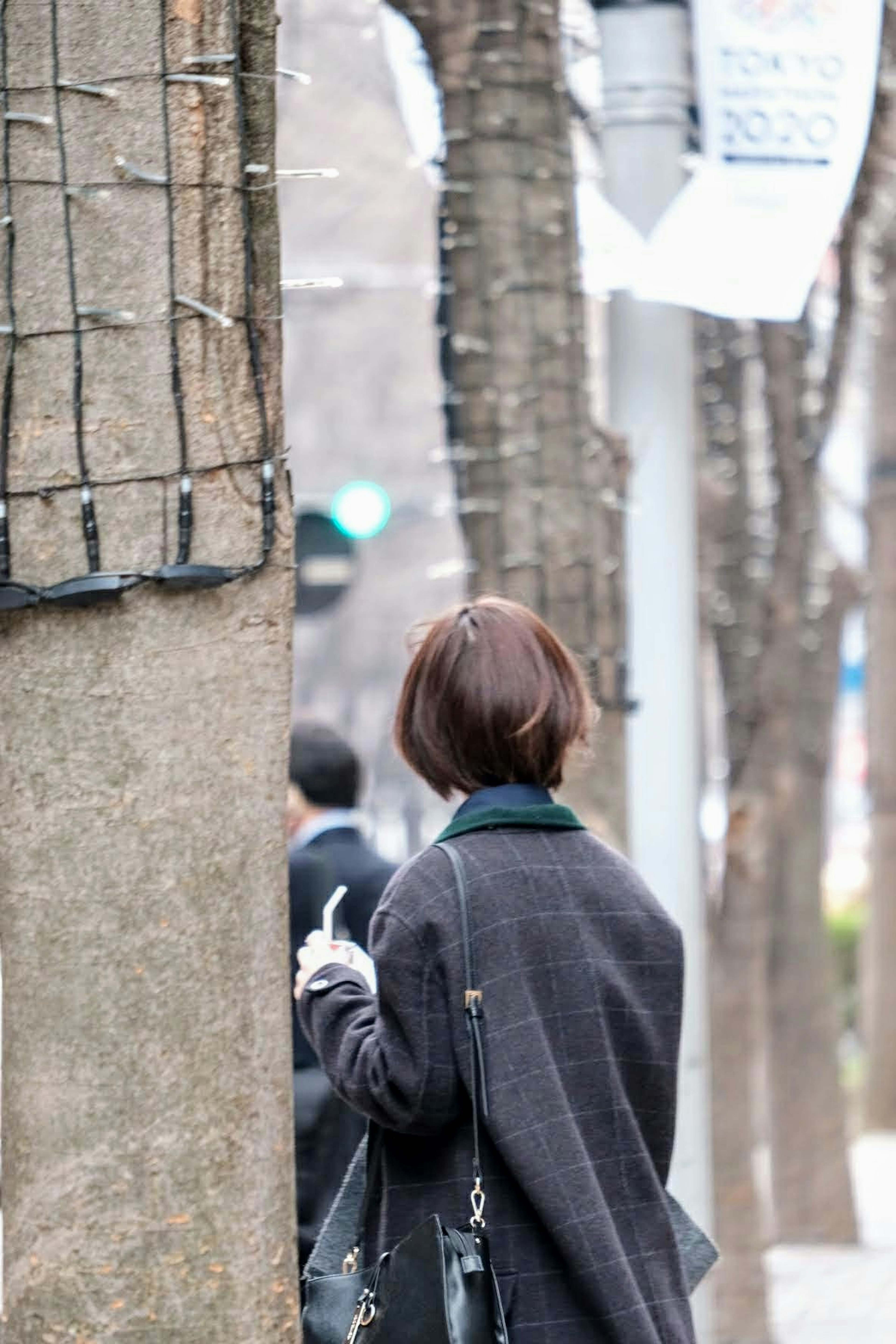 女性が木の陰に立っている街の風景