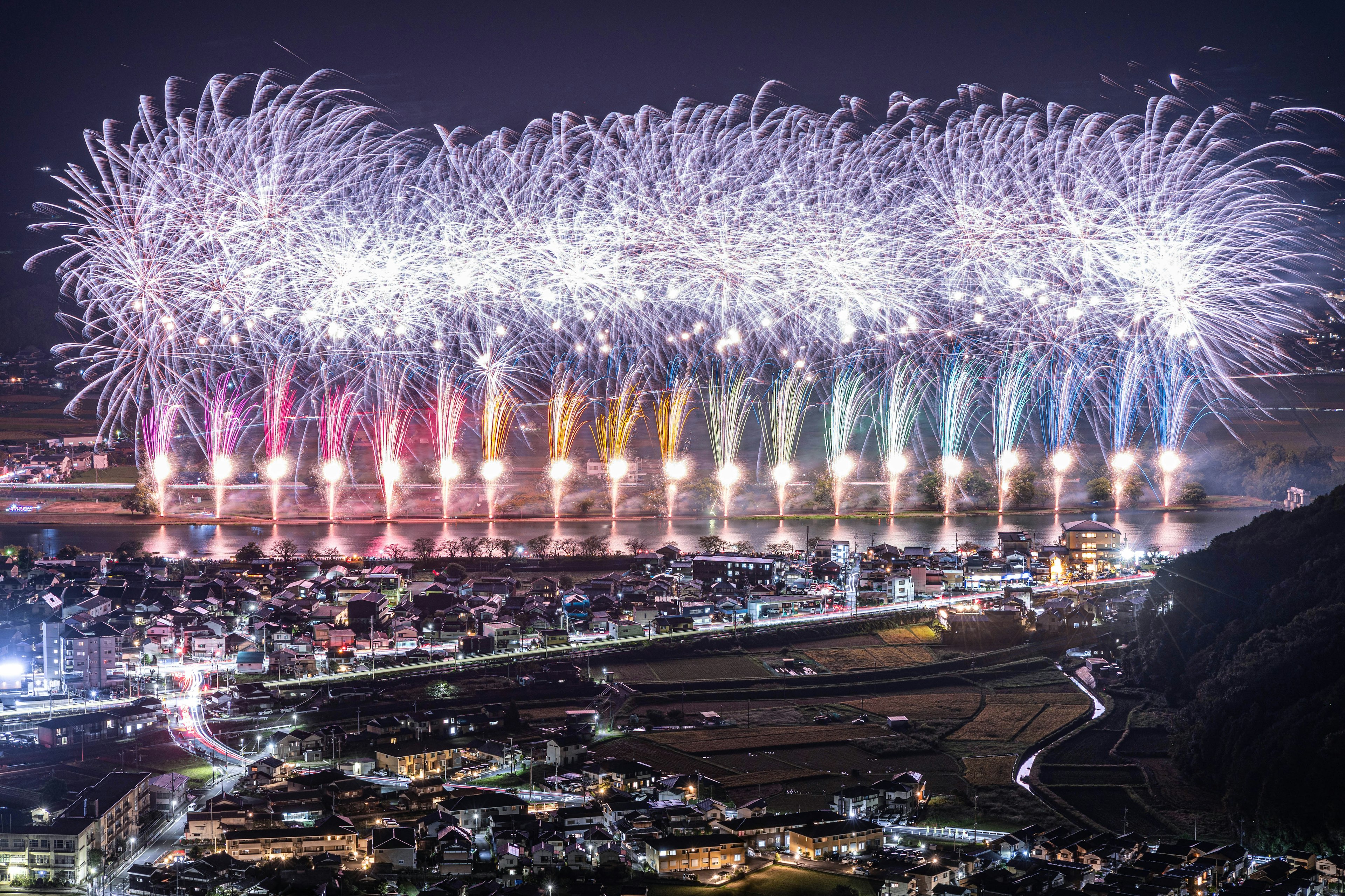 夜空に広がる美しい花火のショーでカラフルな光が川に映る