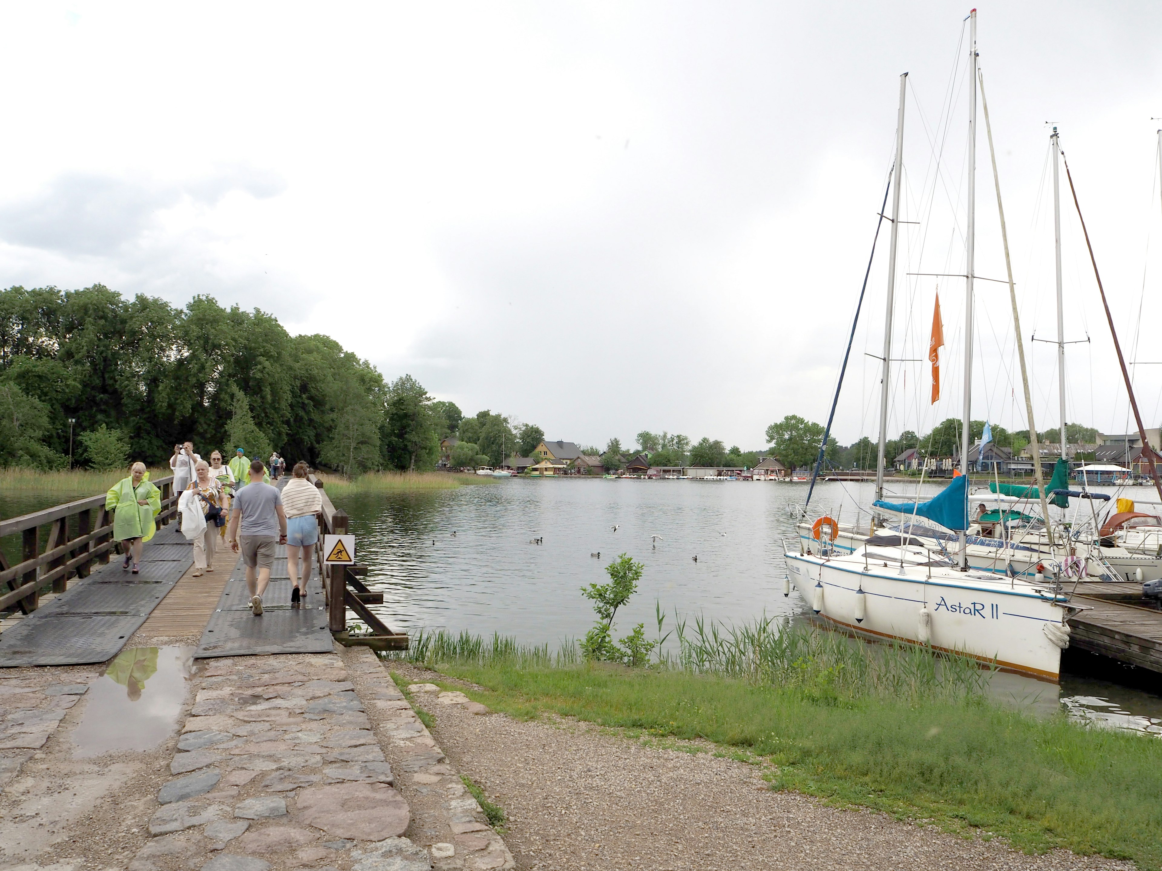 Menschen, die auf einem Weg am See mit festgemachten Booten gehen