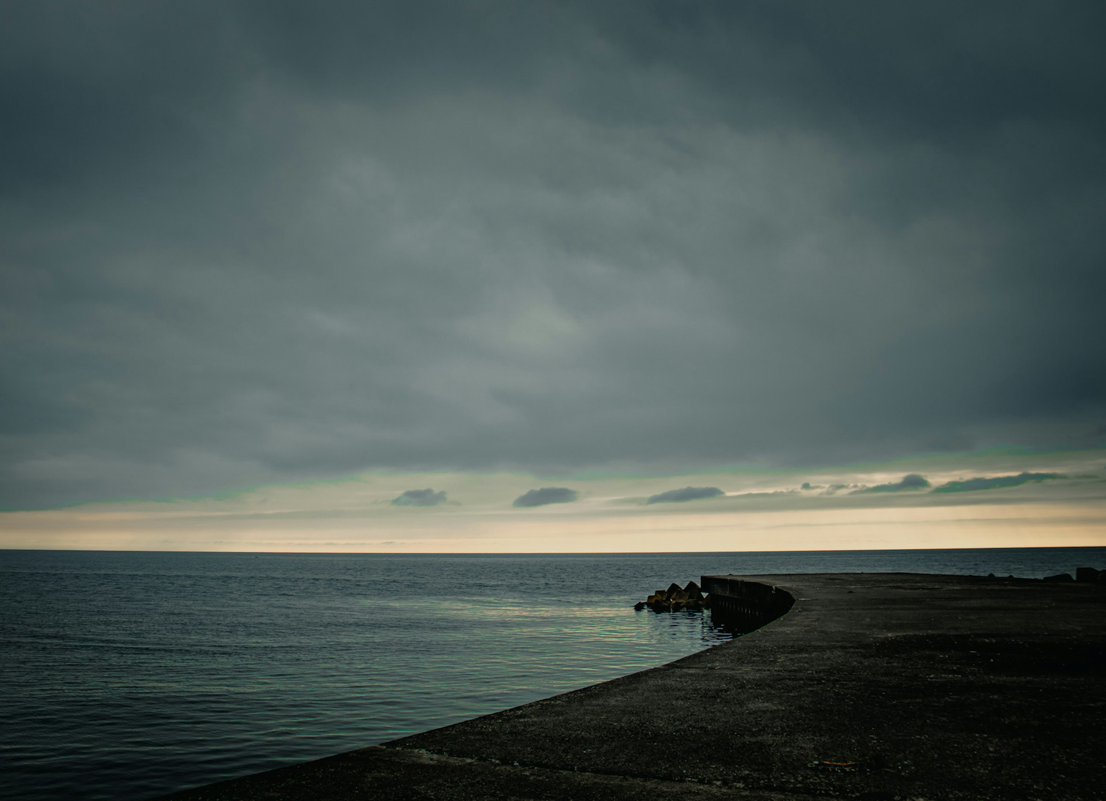 Düstere Küstenlandschaft mit dunklen Wolken und ruhigem Wasser