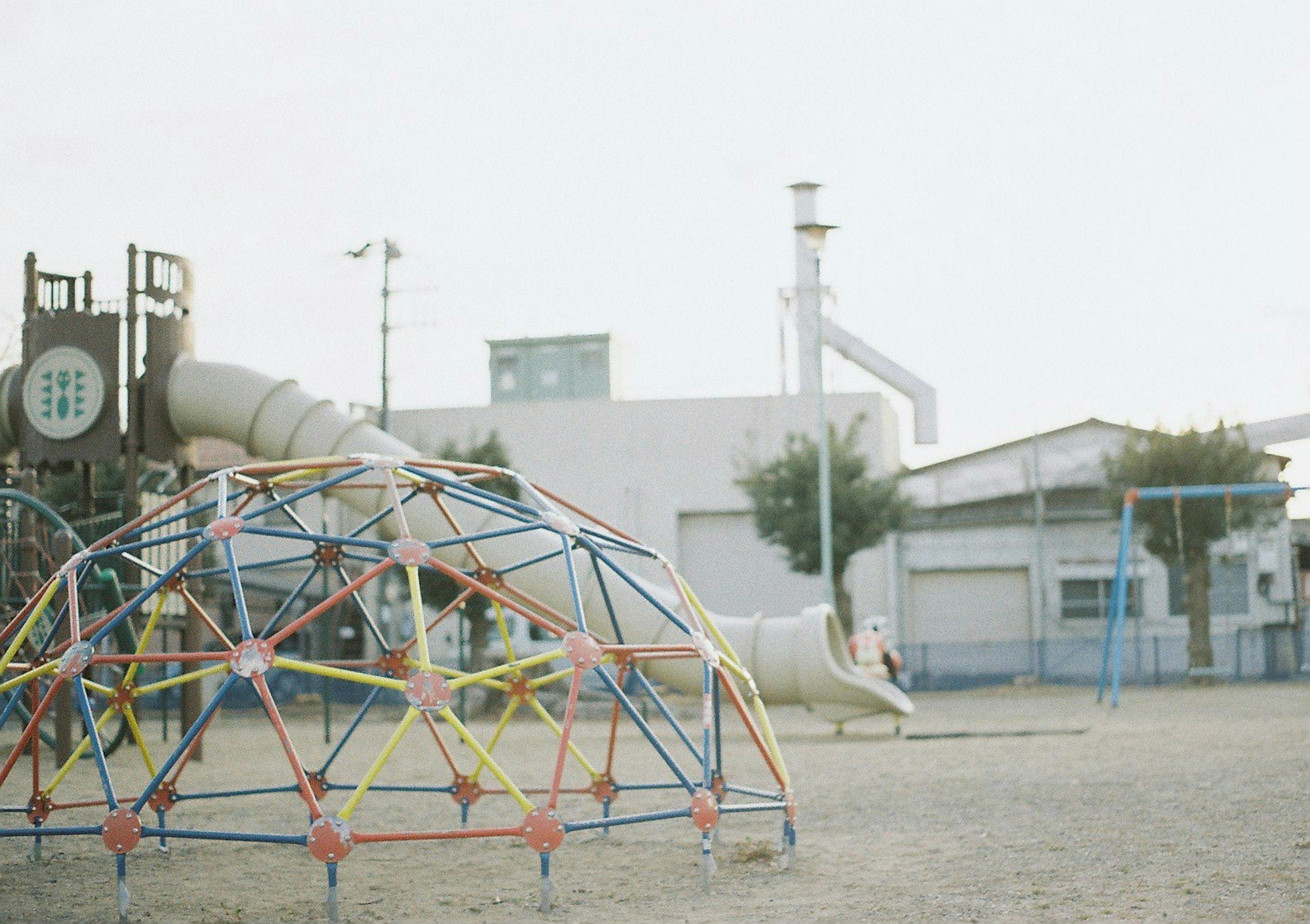 Playground scene with a colorful climbing dome and slide