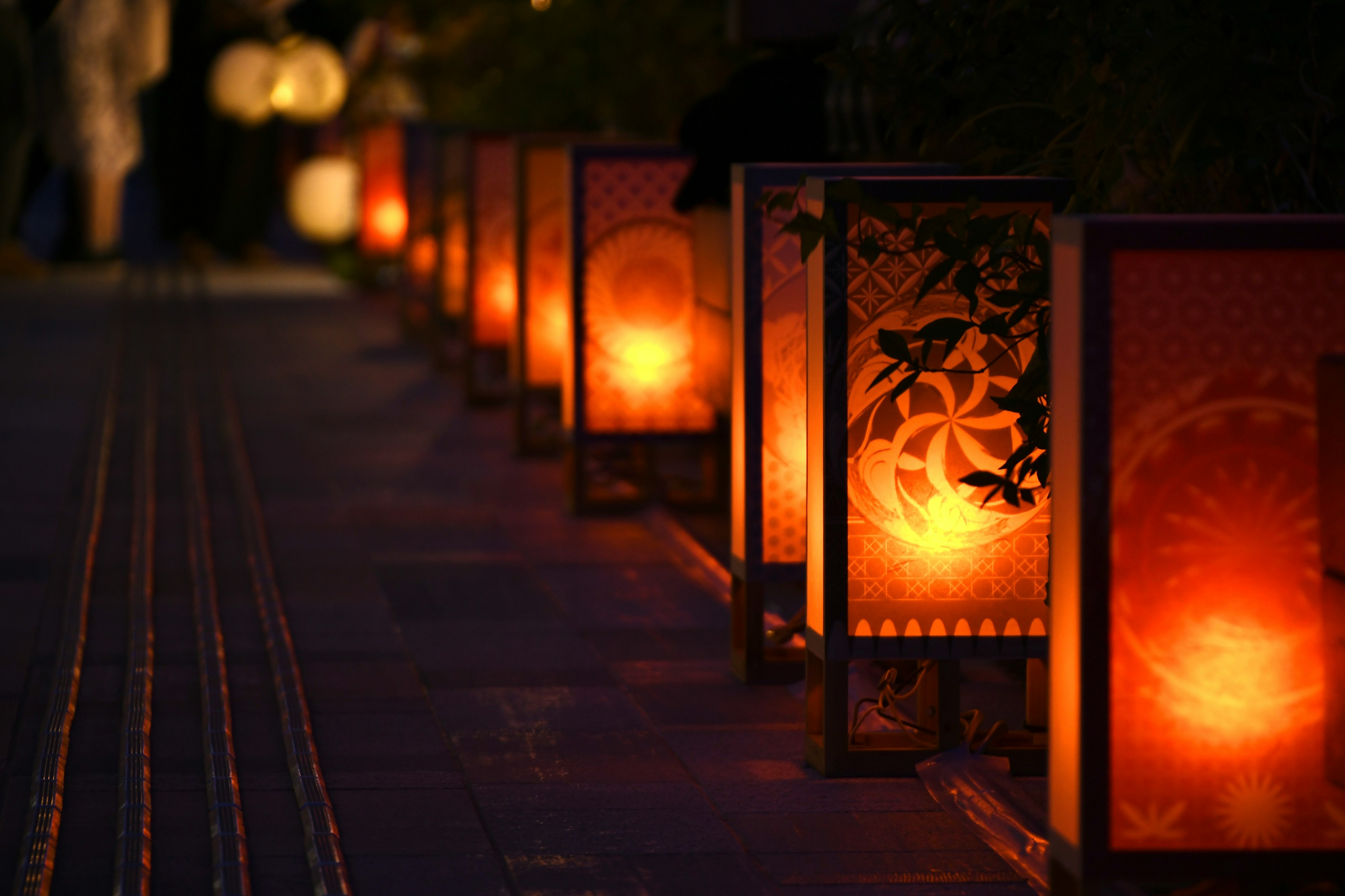 Row of traditional lanterns glowing softly on a nighttime pathway