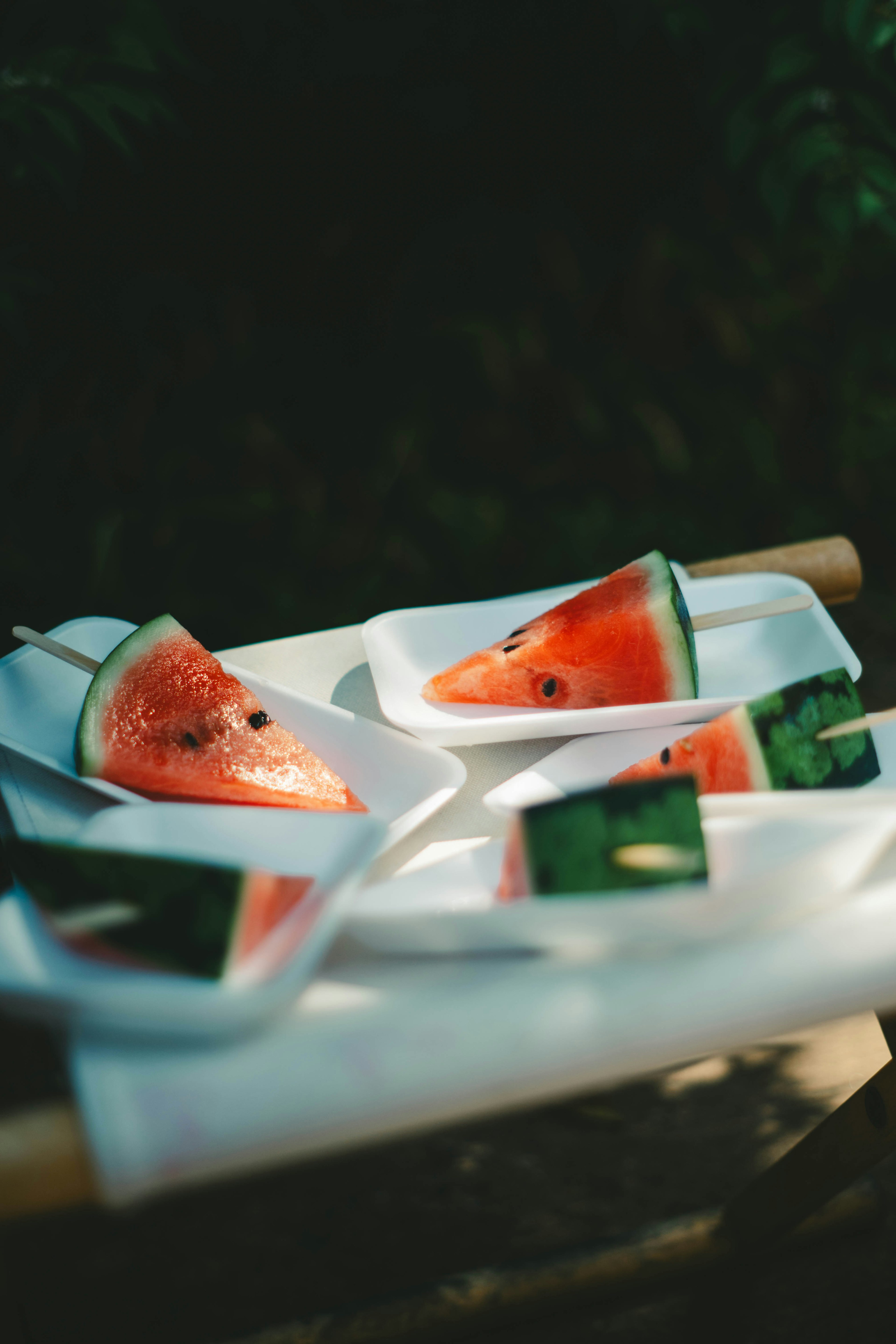 Slices of watermelon on white plates against a green background