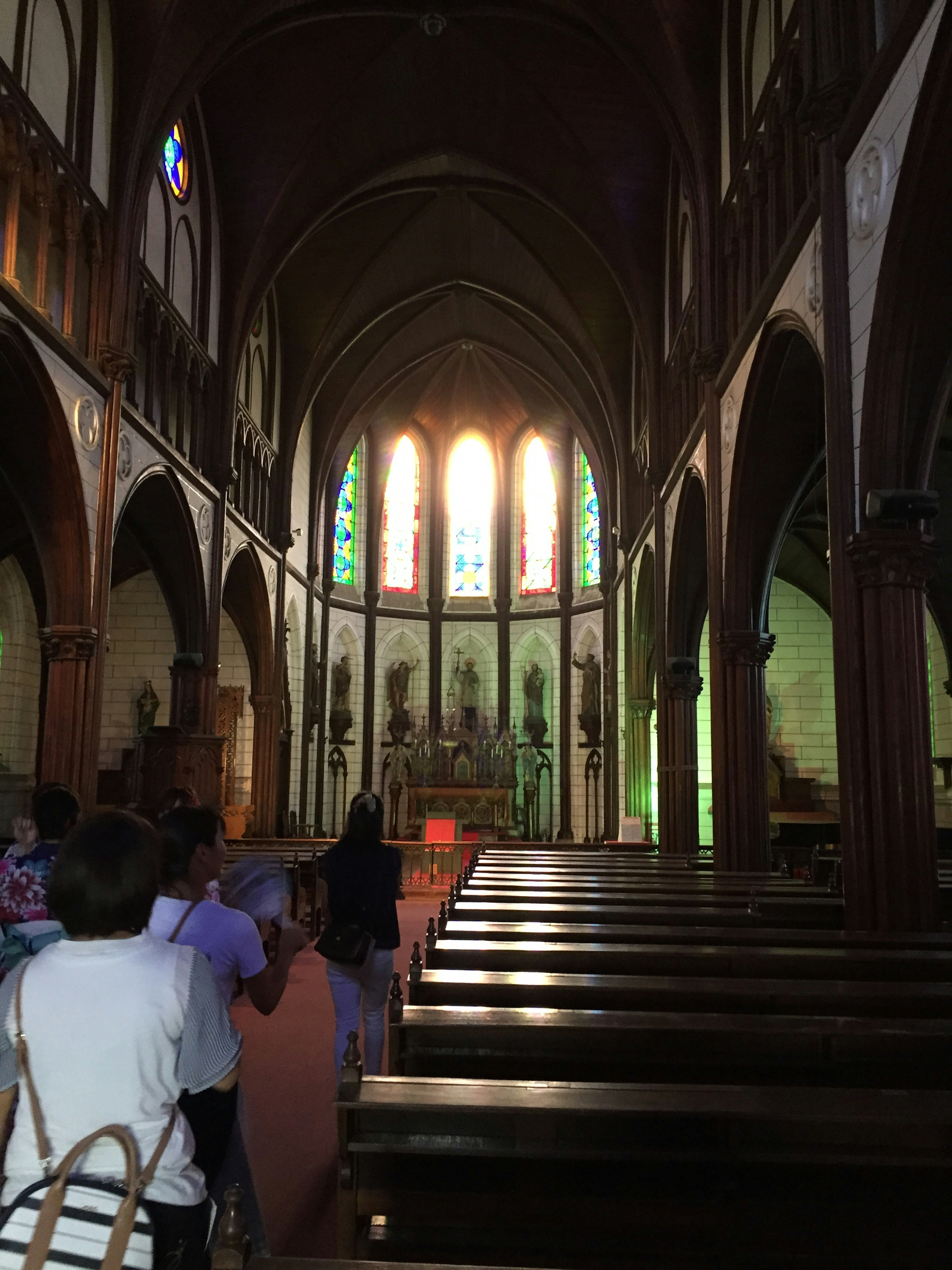 Pemandangan interior gereja yang indah dengan orang-orang berjalan di antara bangku jendela kaca patri berwarna