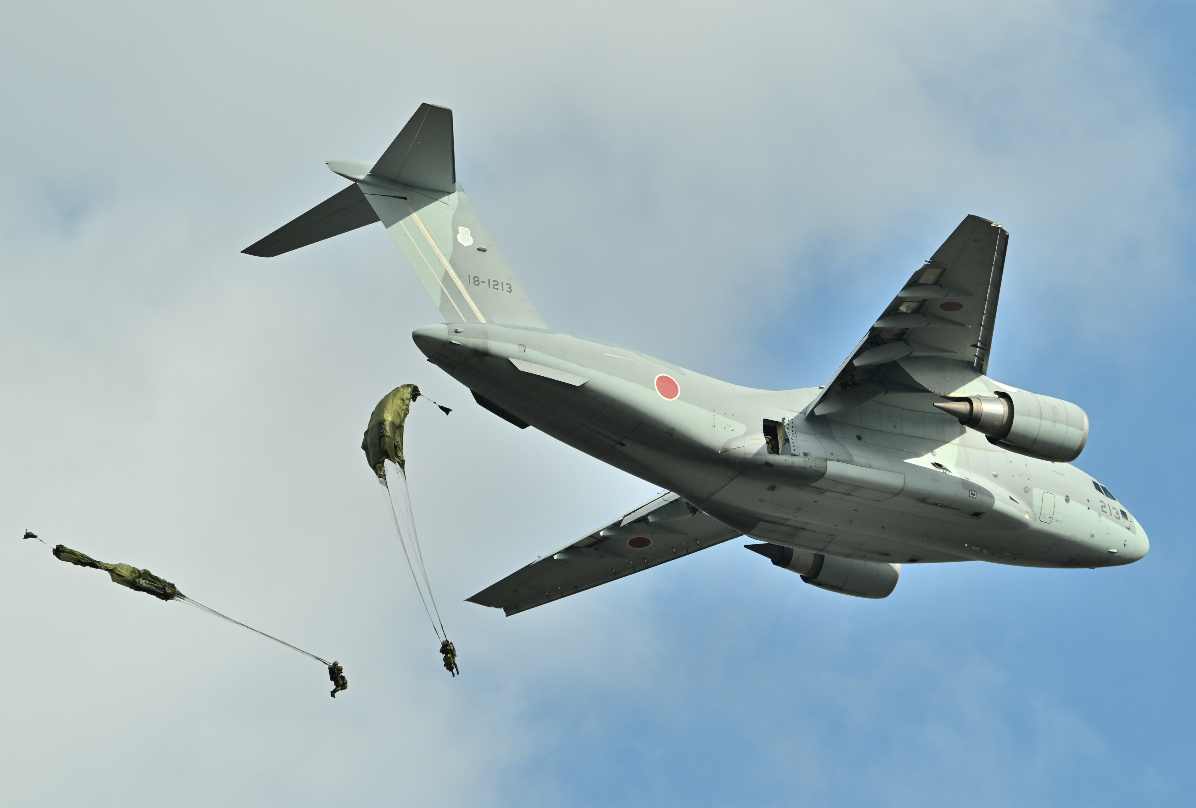 Avión de transporte militar arrojando suministros desde el cielo