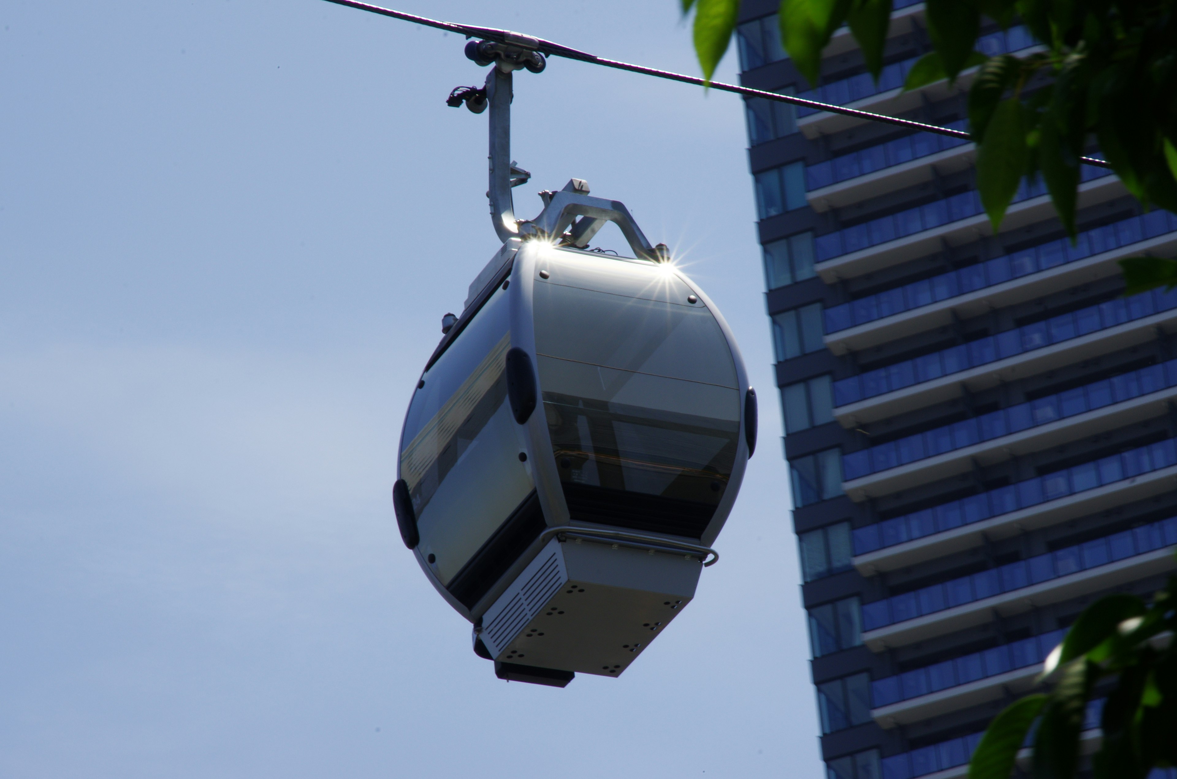 Un teleférico cerca de un rascacielos bajo un cielo azul claro