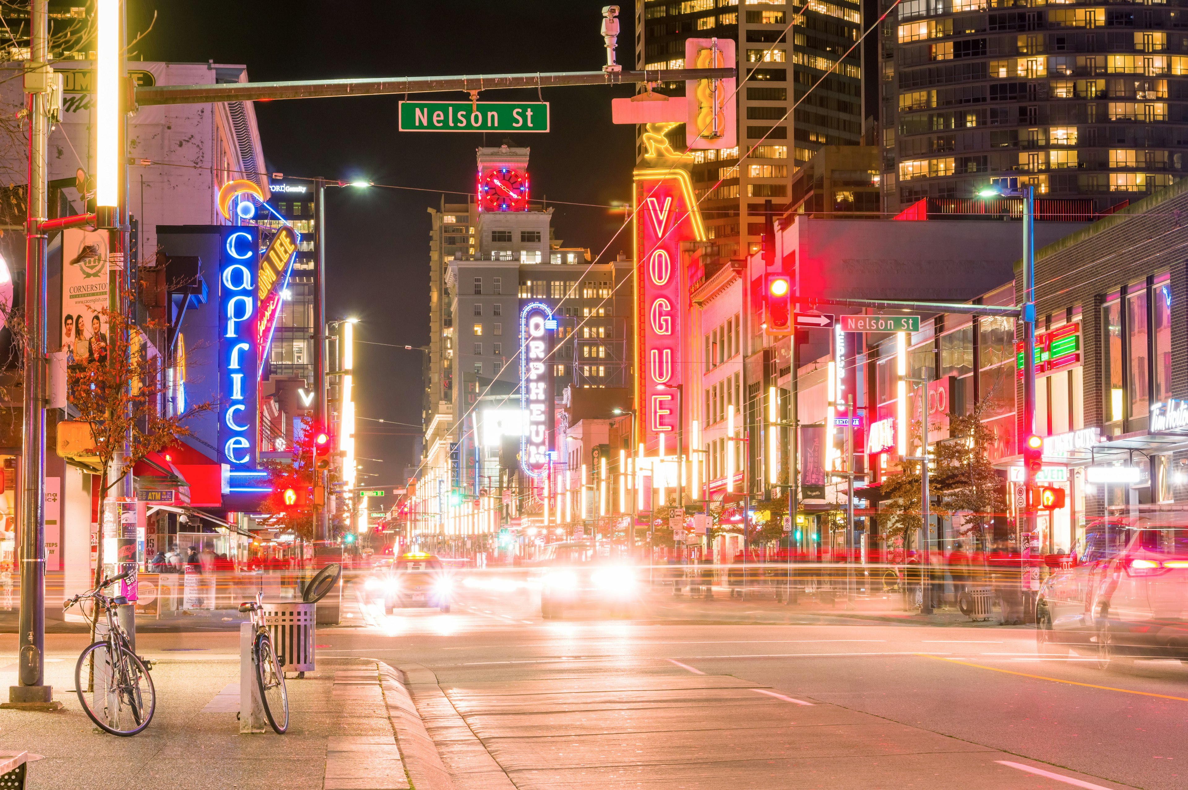 Night cityscape featuring bright neon signs along the street bicycles parked on the sidewalk