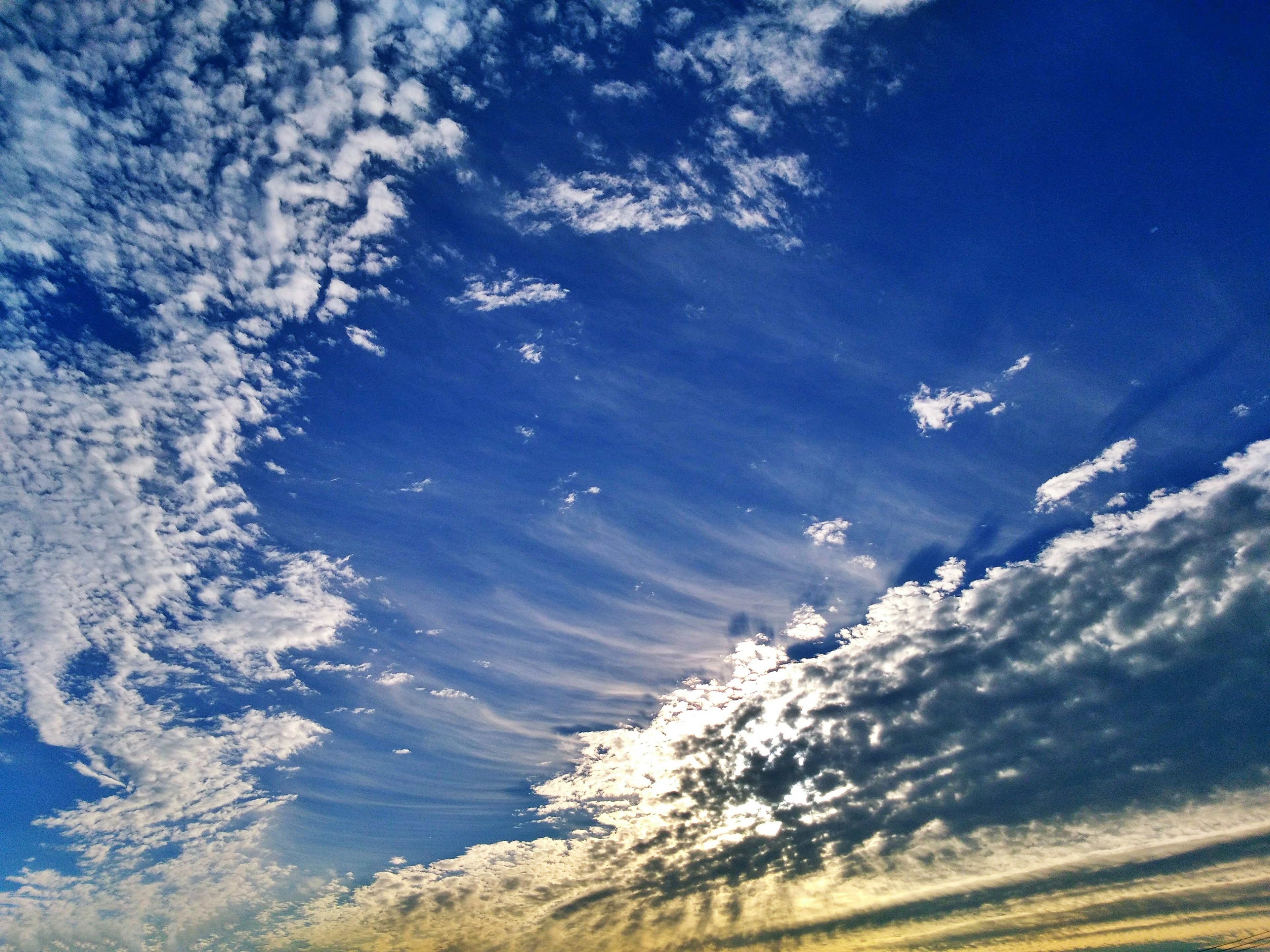 Ciel bleu vibrant avec des nuages blancs et une lumière dorée