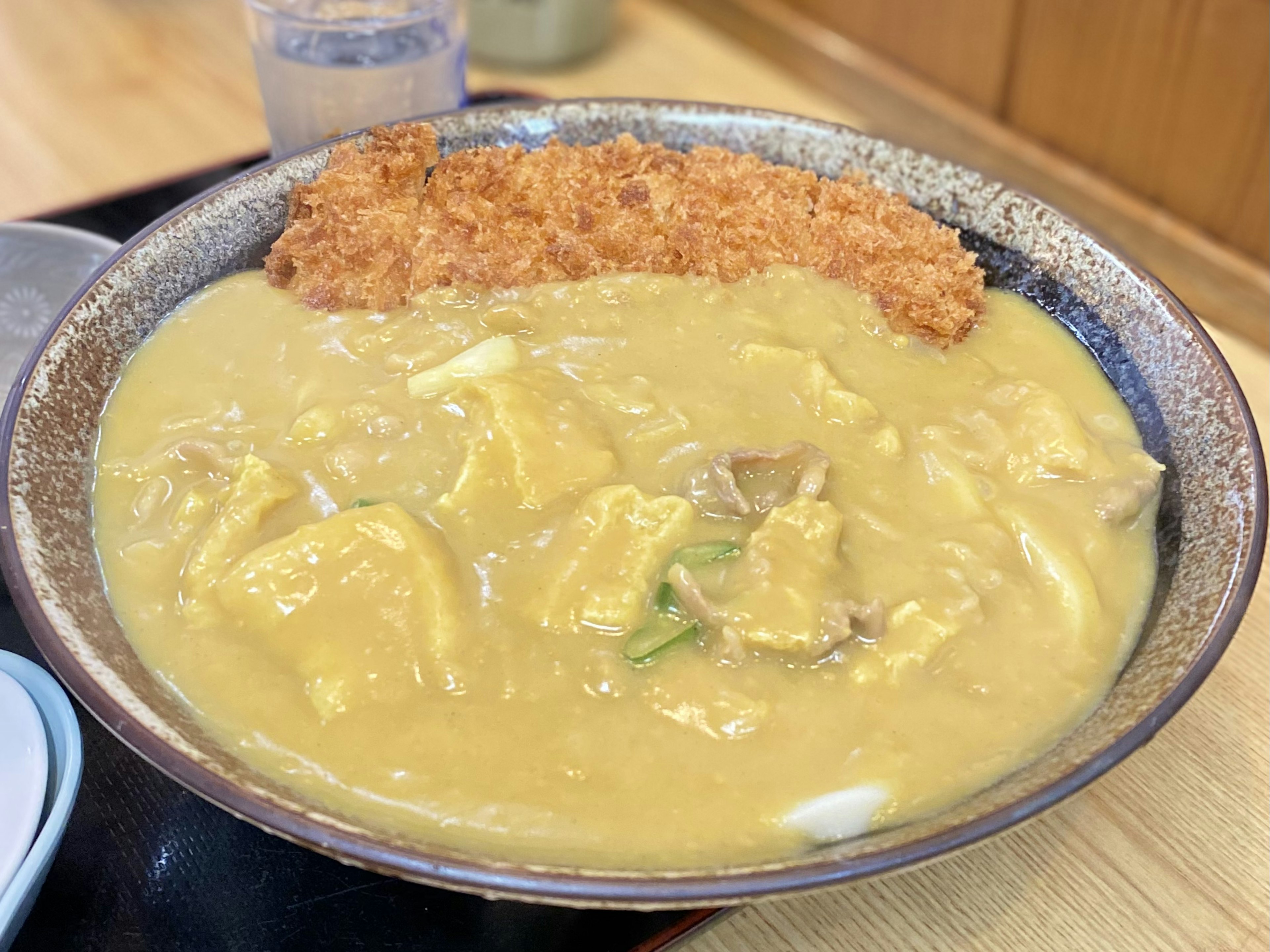 クリーミーなカレーソースの上に鶏肉と卵が載った丼料理とサクサクのトンカツ