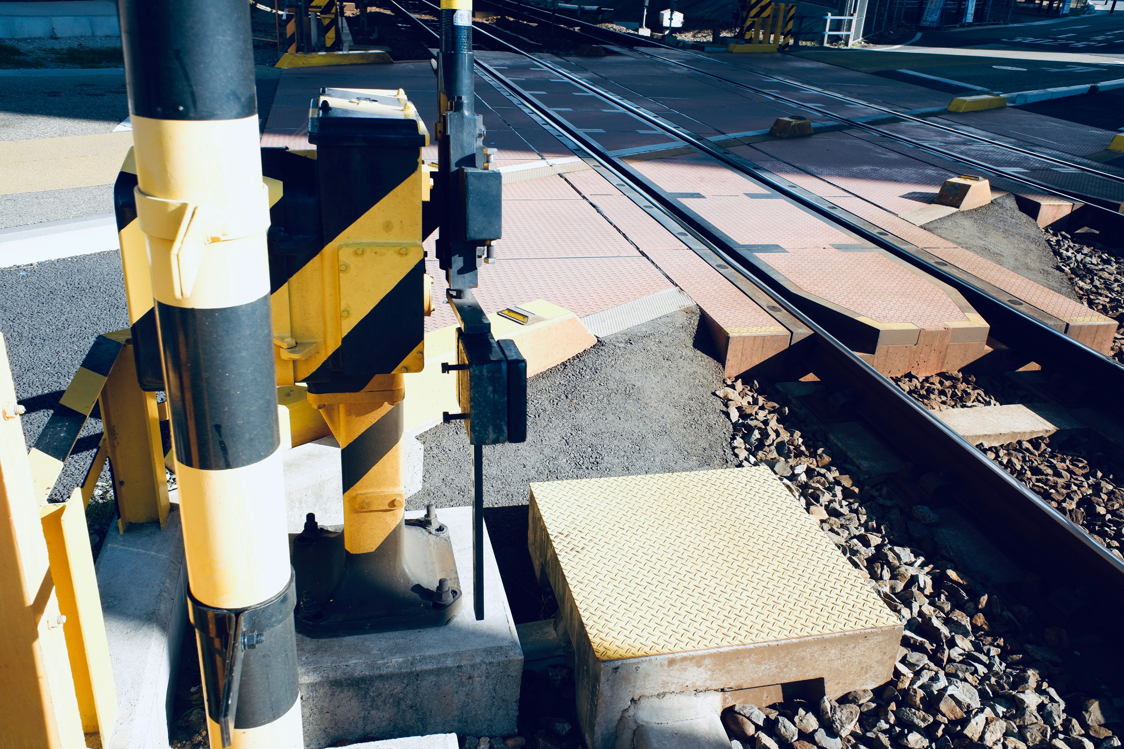 Railroad crossing safety equipment with yellow striped pole near the tracks