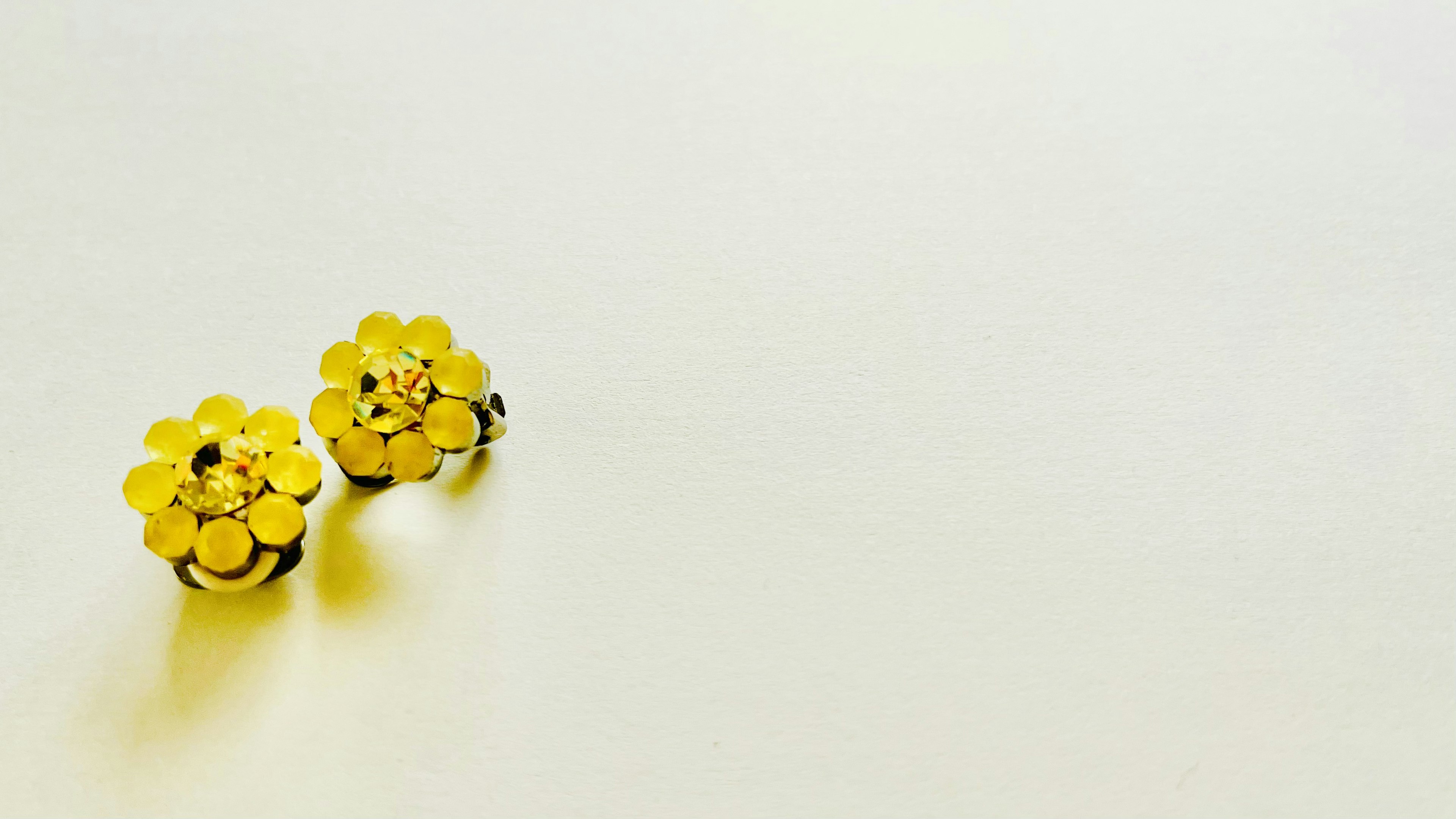 Yellow flower-shaped earrings placed on a white background