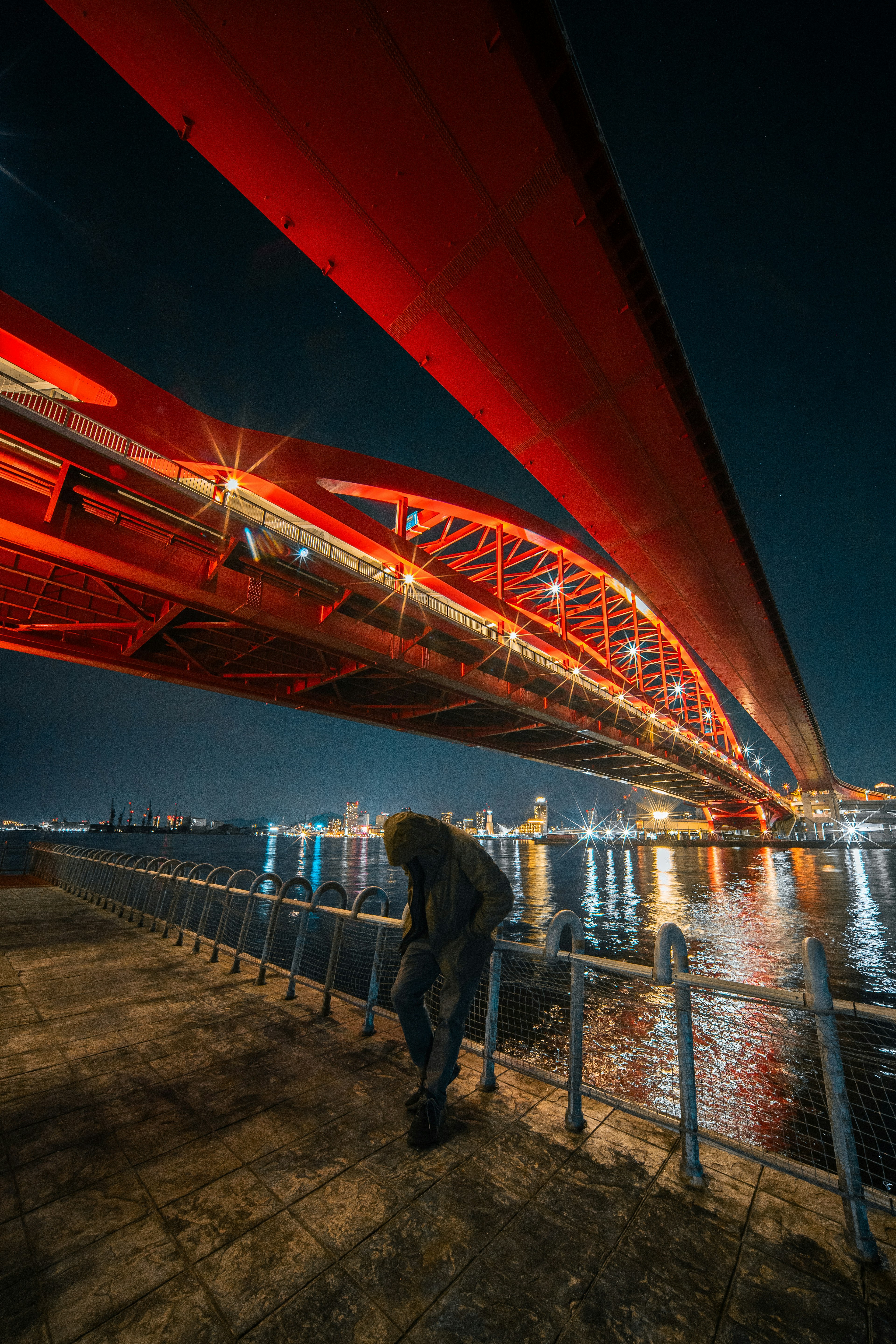 Red bridge illuminated at night with reflections on the water