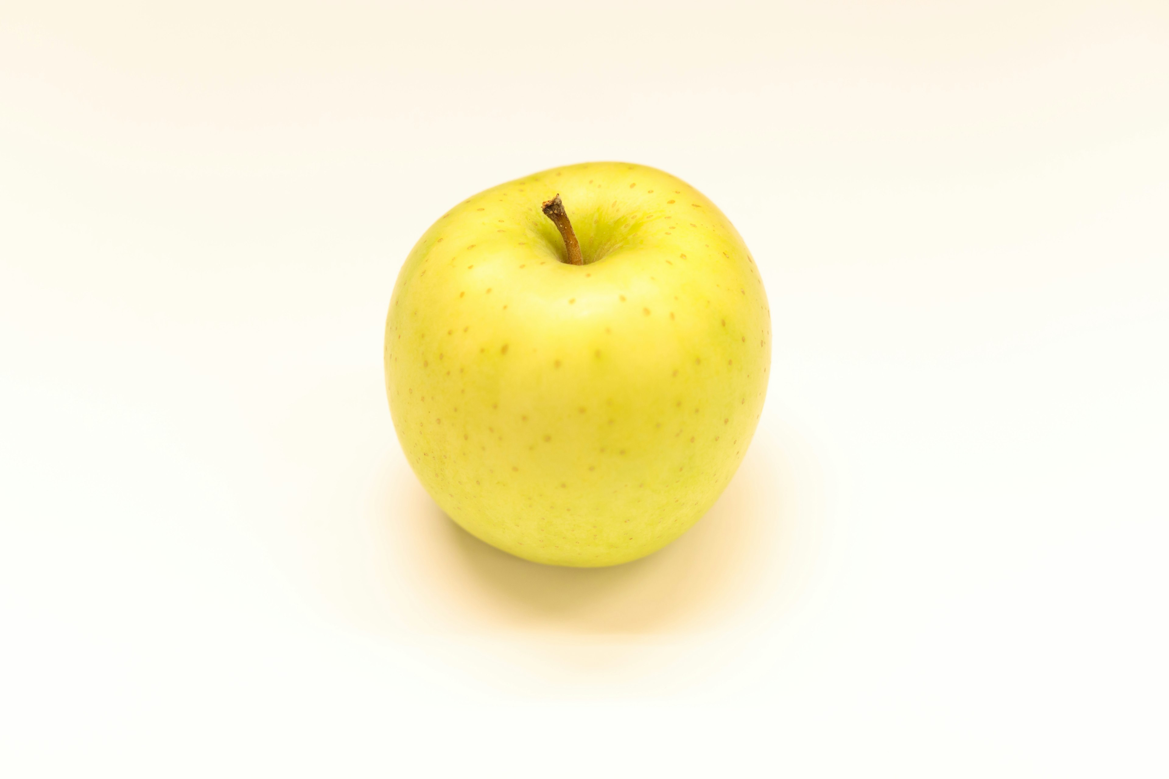 A yellow apple placed on a white background