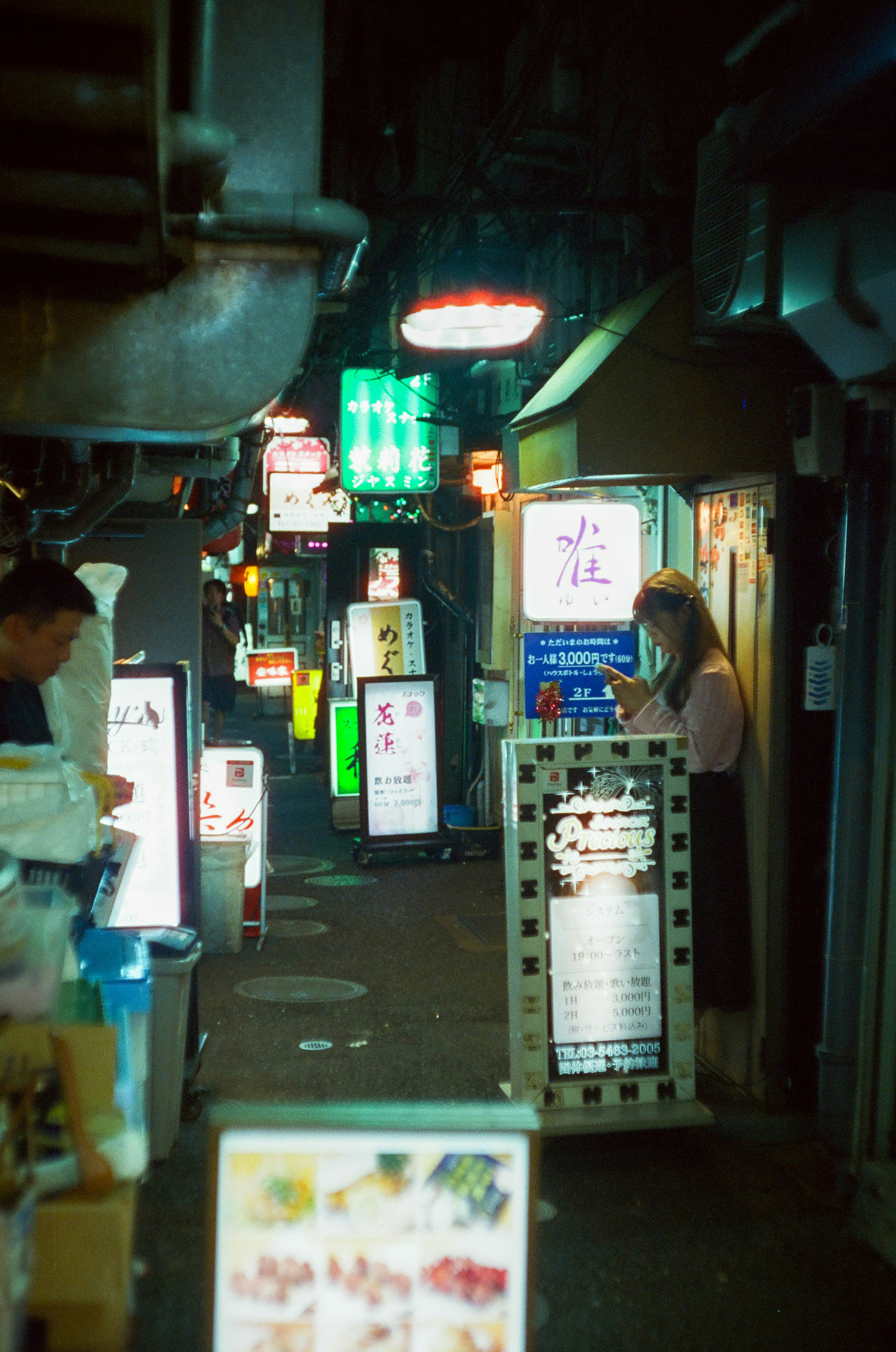 Narrow alleyway lined with neon signs and shop entrances