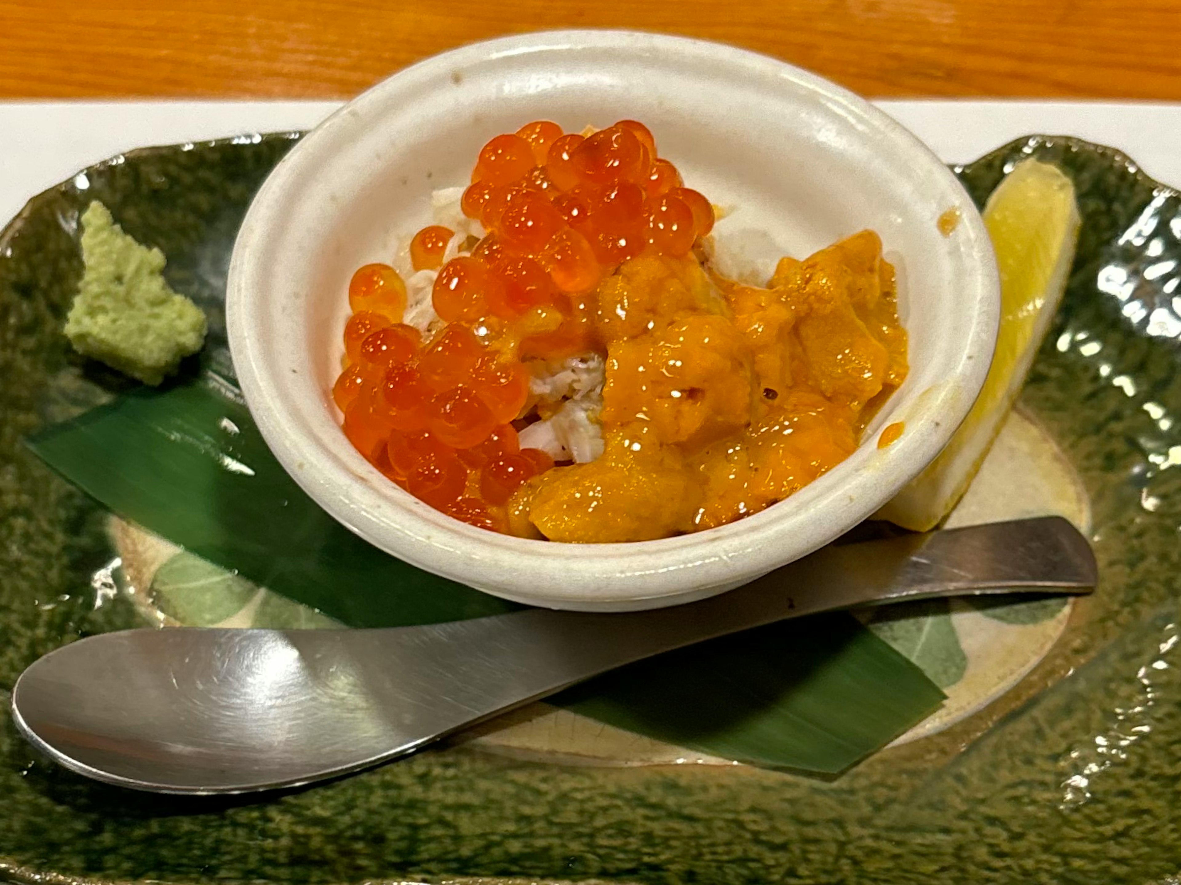 A small dish featuring creamy sea urchin and vibrant salmon roe served with wasabi and lemon