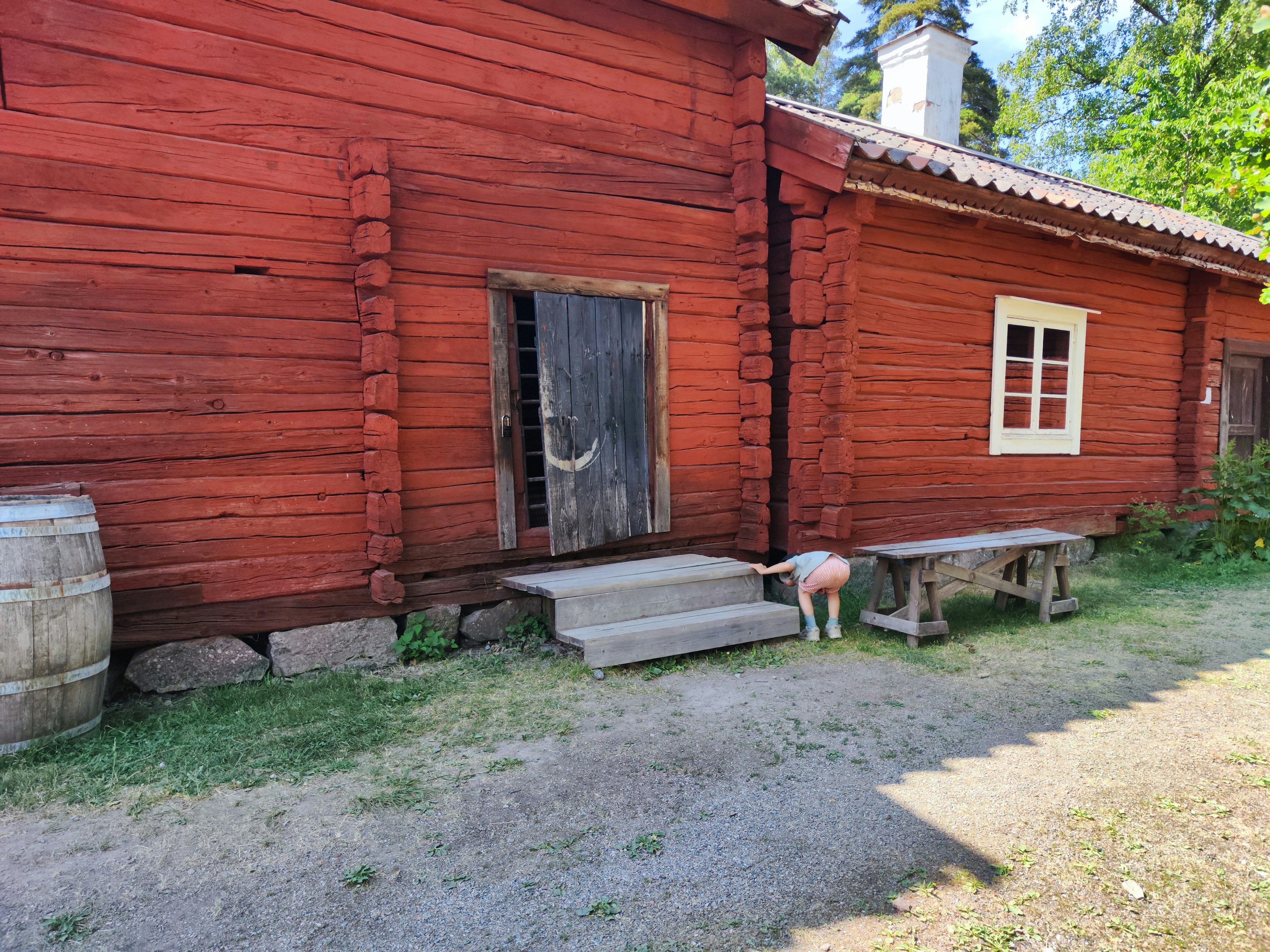 Außenansicht eines roten Holzhauses mit einem Hund in der Nähe