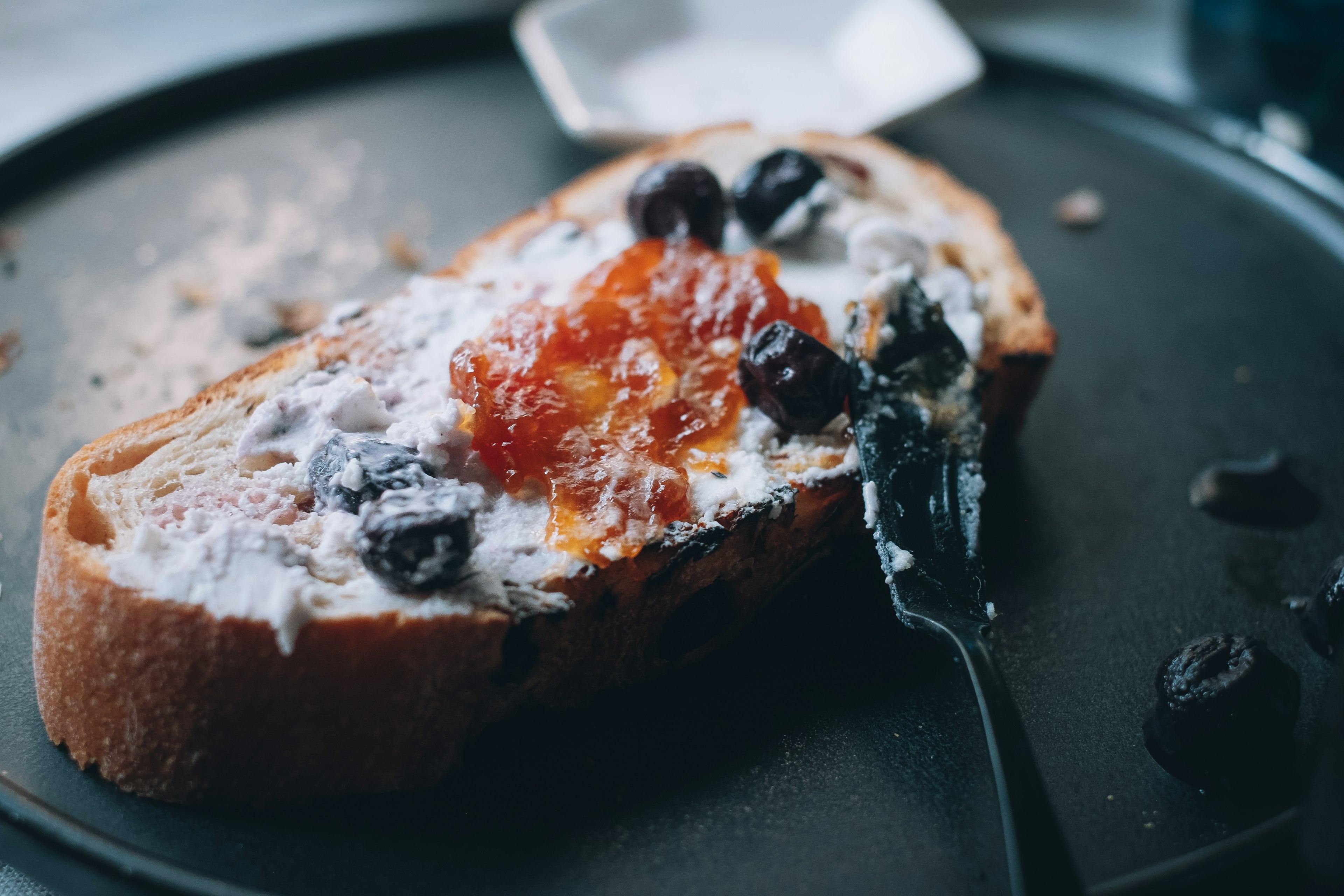 Toast topped with cream cheese and jam on a dark plate