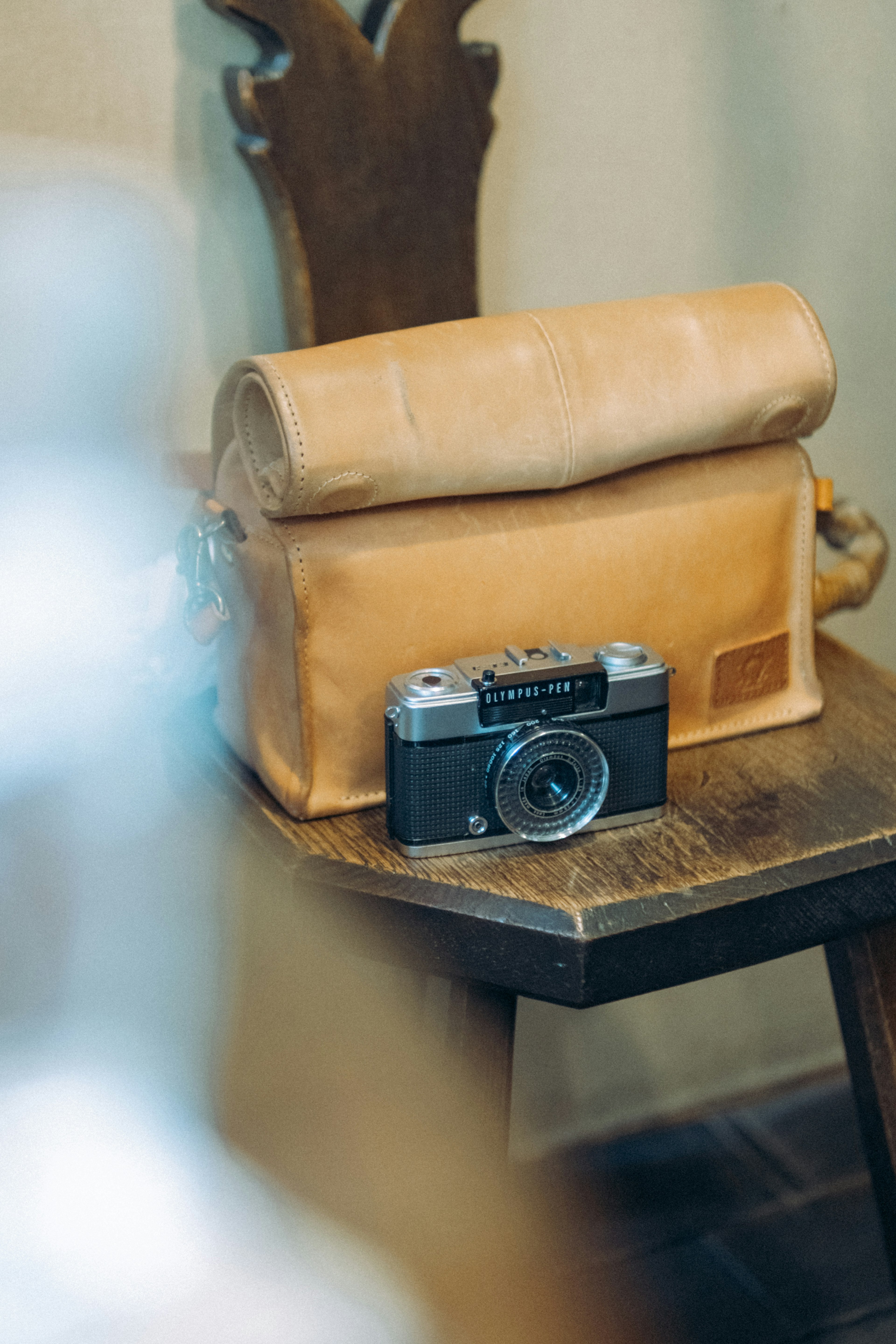 Eine Kamera und eine Ledertasche auf einem Holztisch