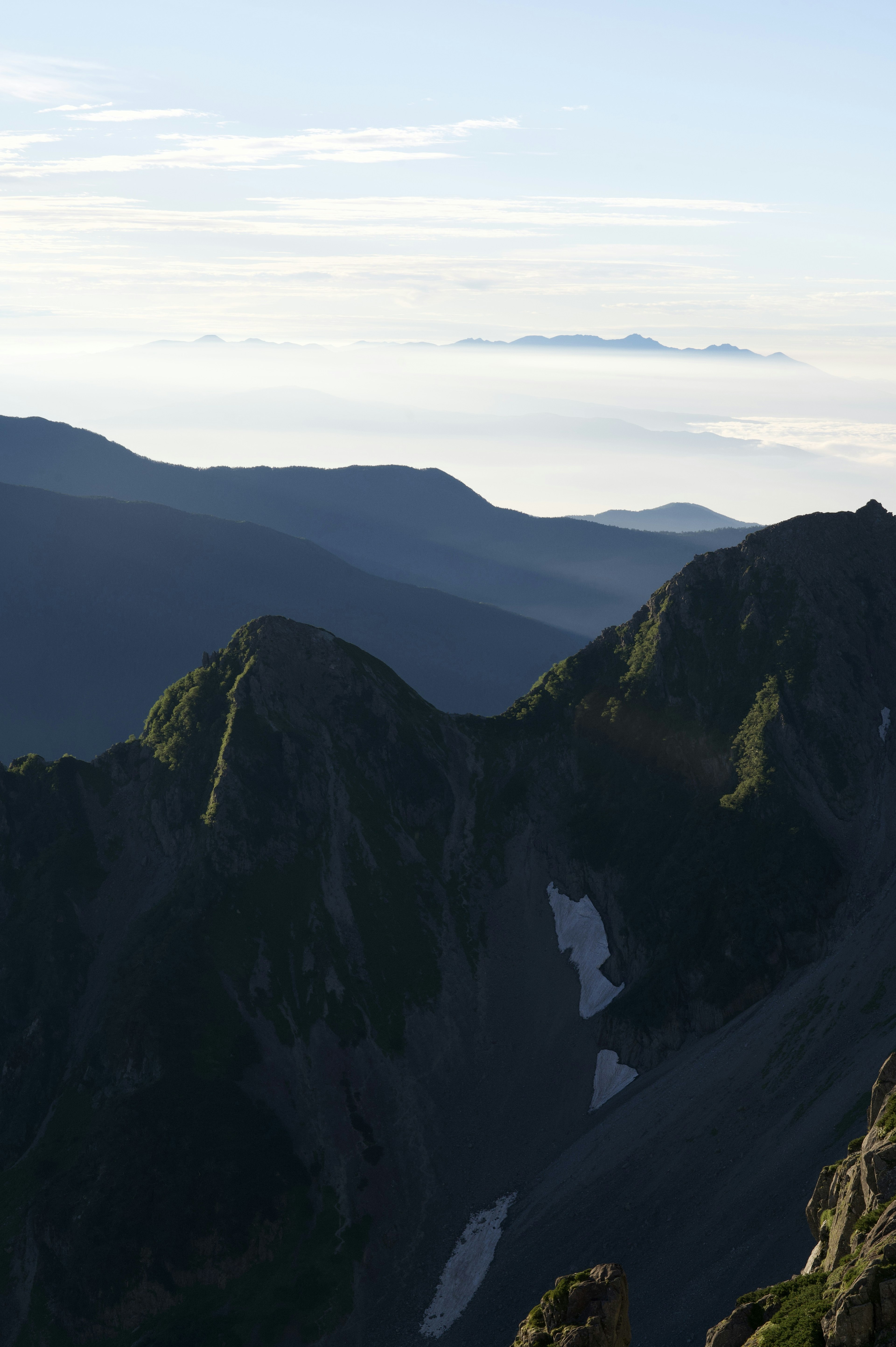 Silhouette di montagne con un mare di nuvole sullo sfondo e cielo blu