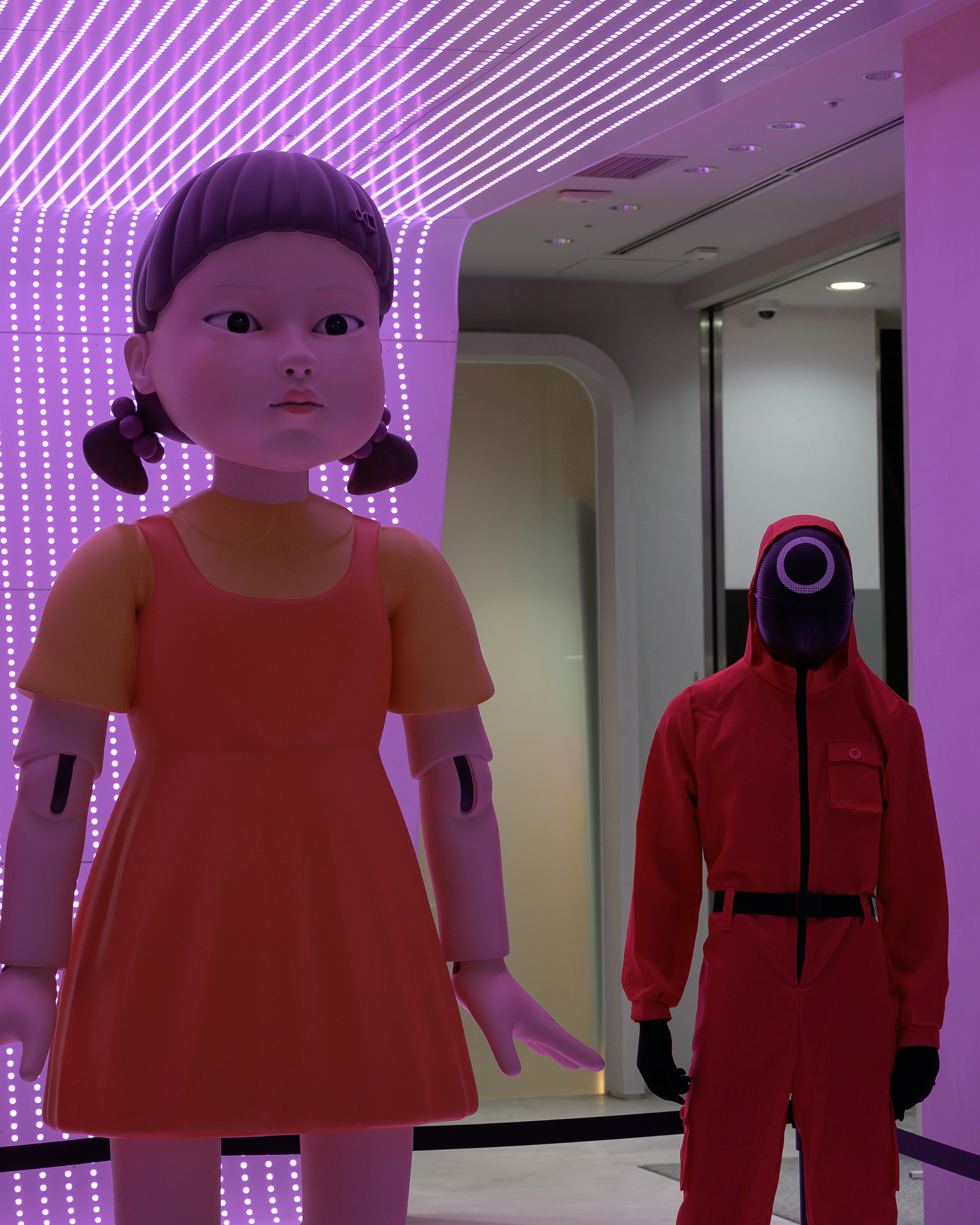 Gran muñeca y personaje con traje rojo en un entorno futurista