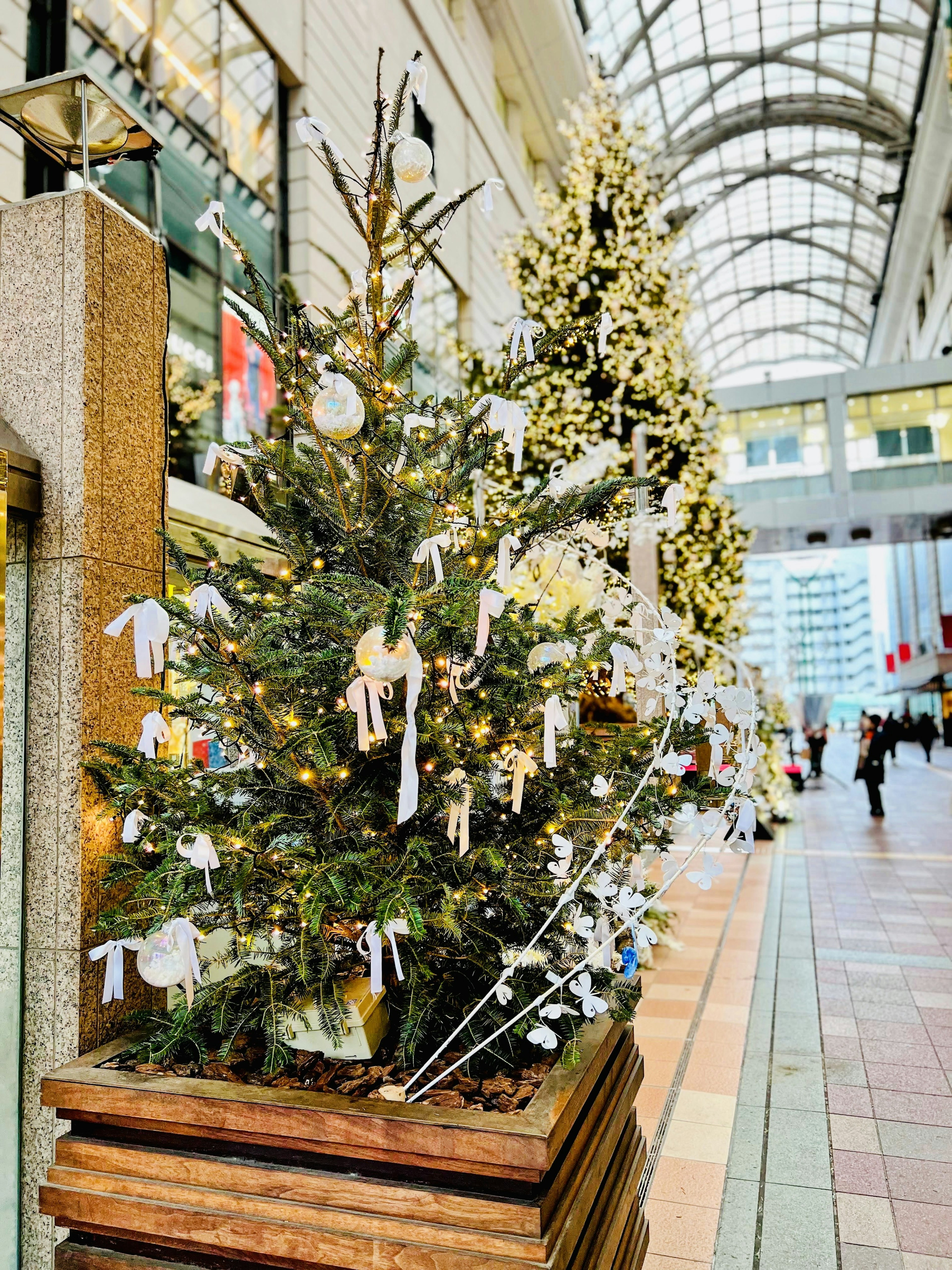 A decorated Christmas tree with lights and ornaments in a shopping arcade