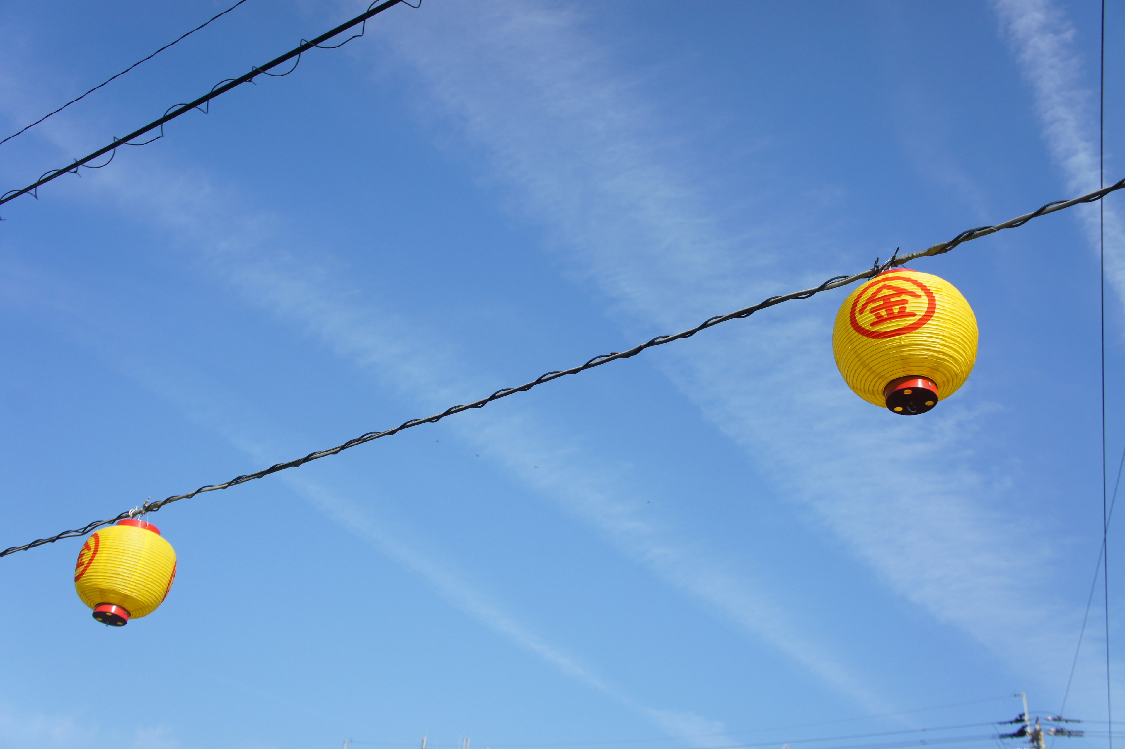 Two yellow lanterns hanging against a blue sky