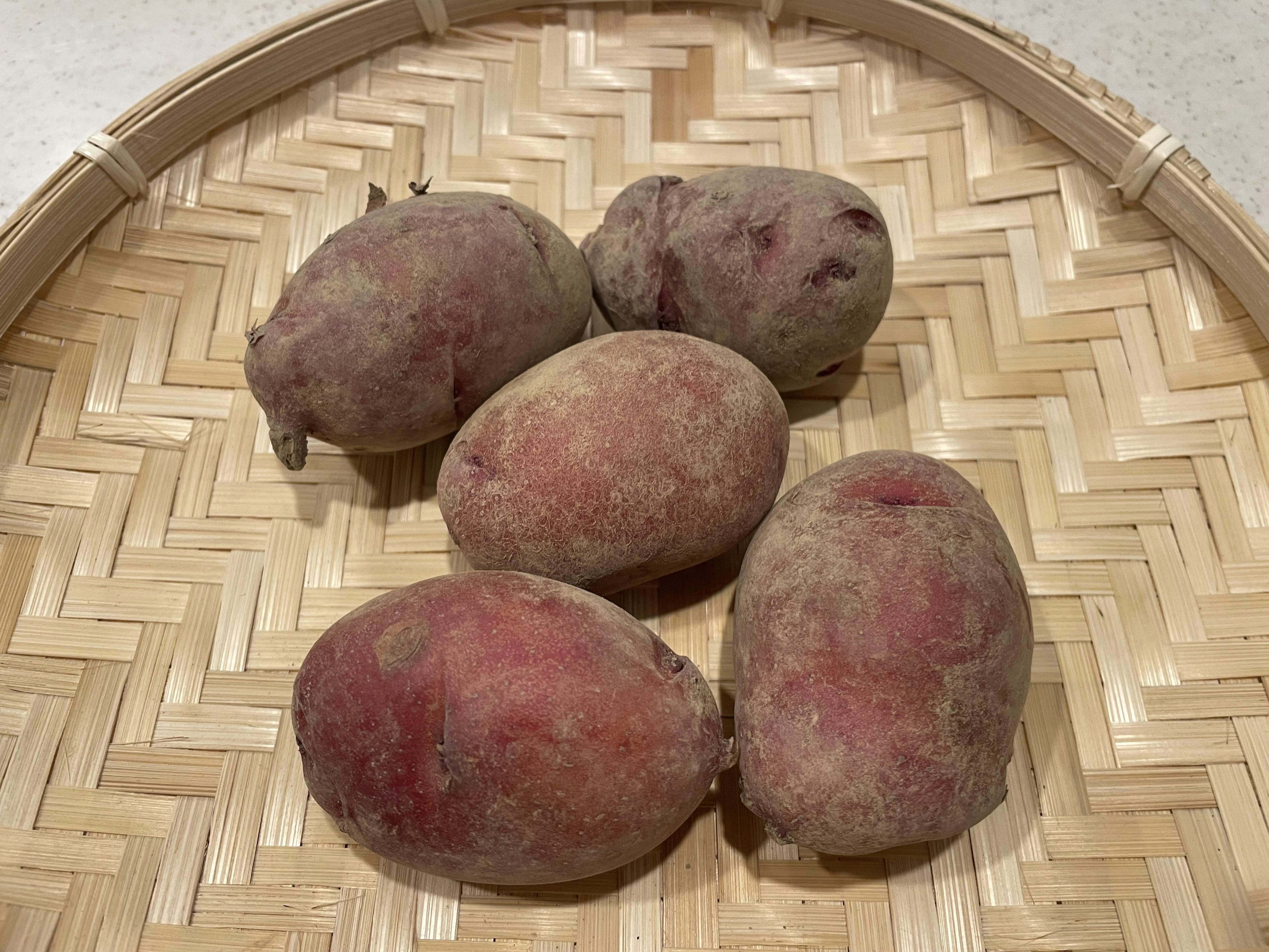 Five sweet potatoes on a woven basket