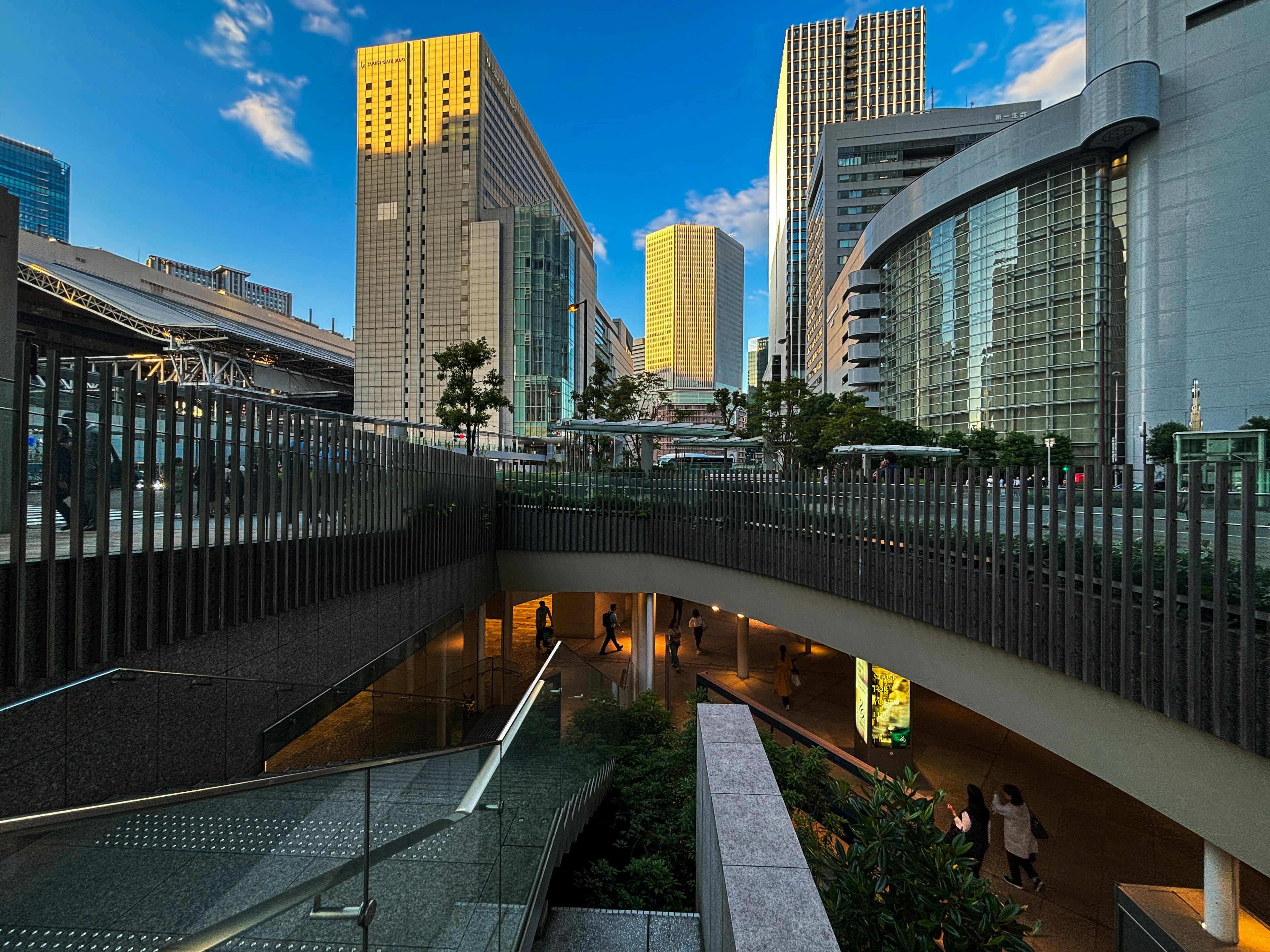 都市の高層ビルと青空が広がる風景 橋のような構造物と緑の植栽