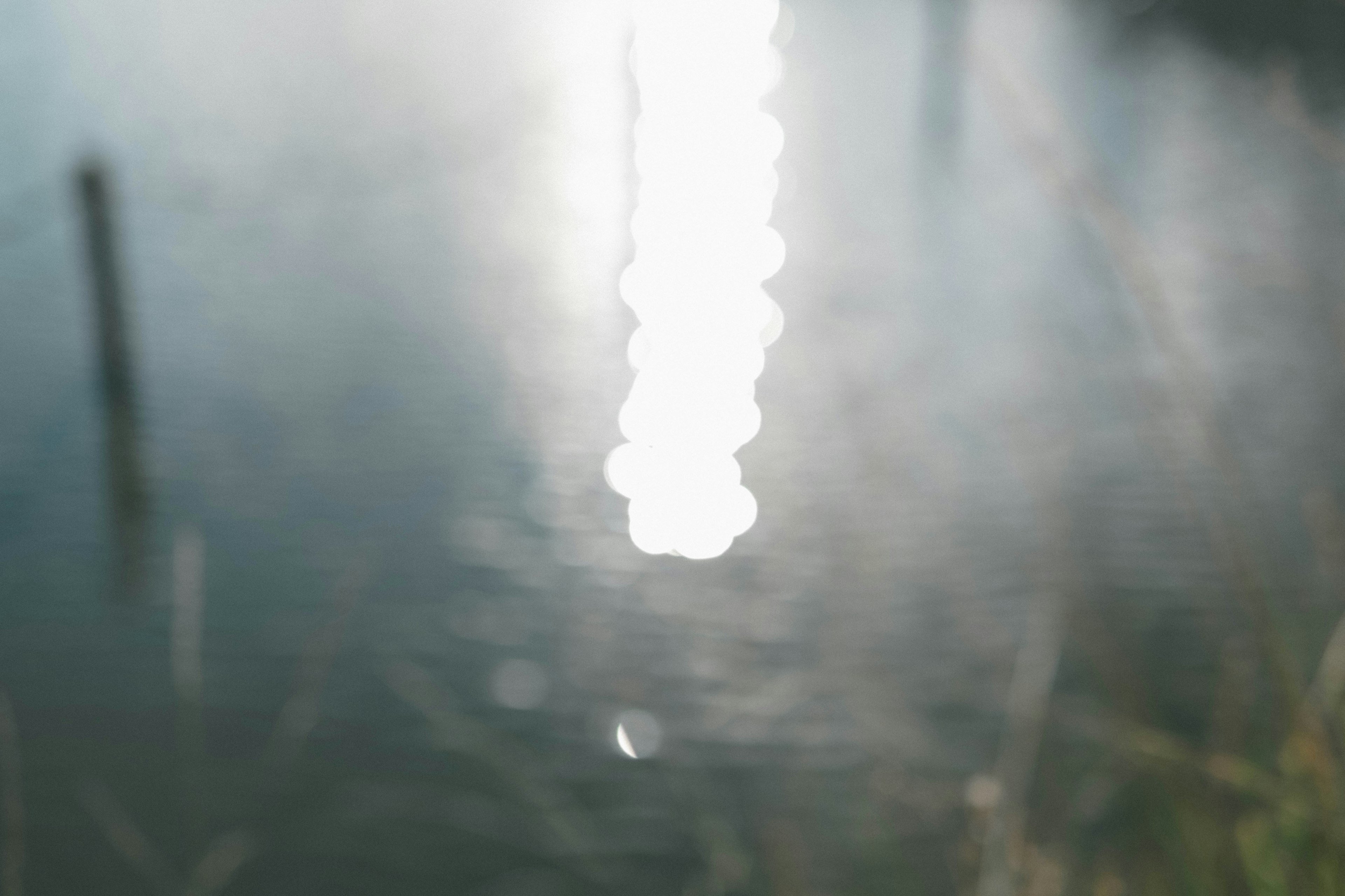 Verschommene Lichtreflexion auf der Wasseroberfläche mit Gras