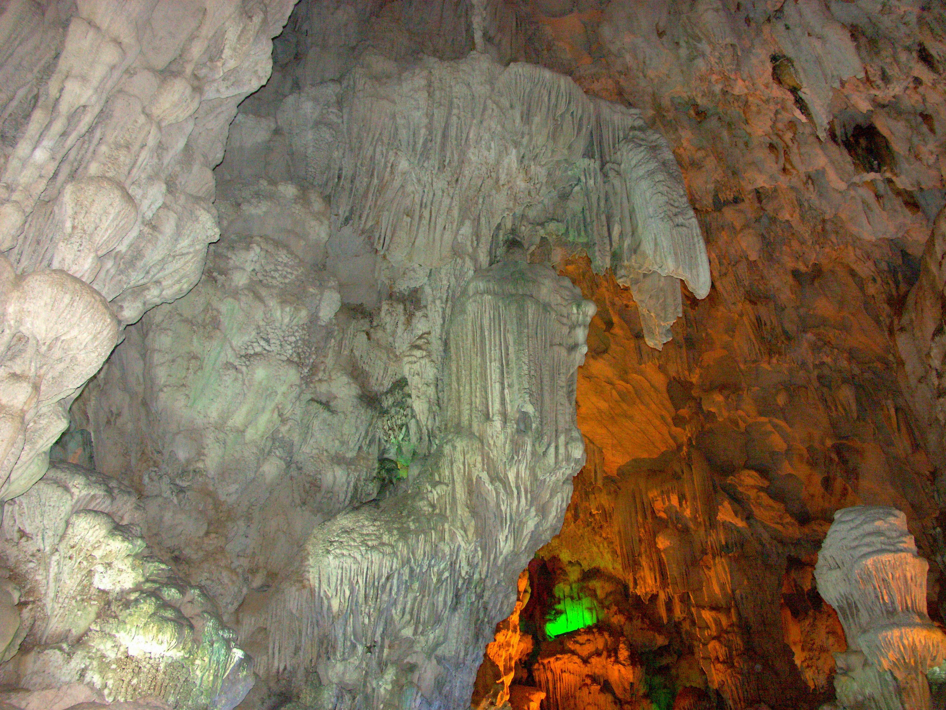 Interior de una cueva con iluminación colorida que destaca formaciones de piedra caliza natural