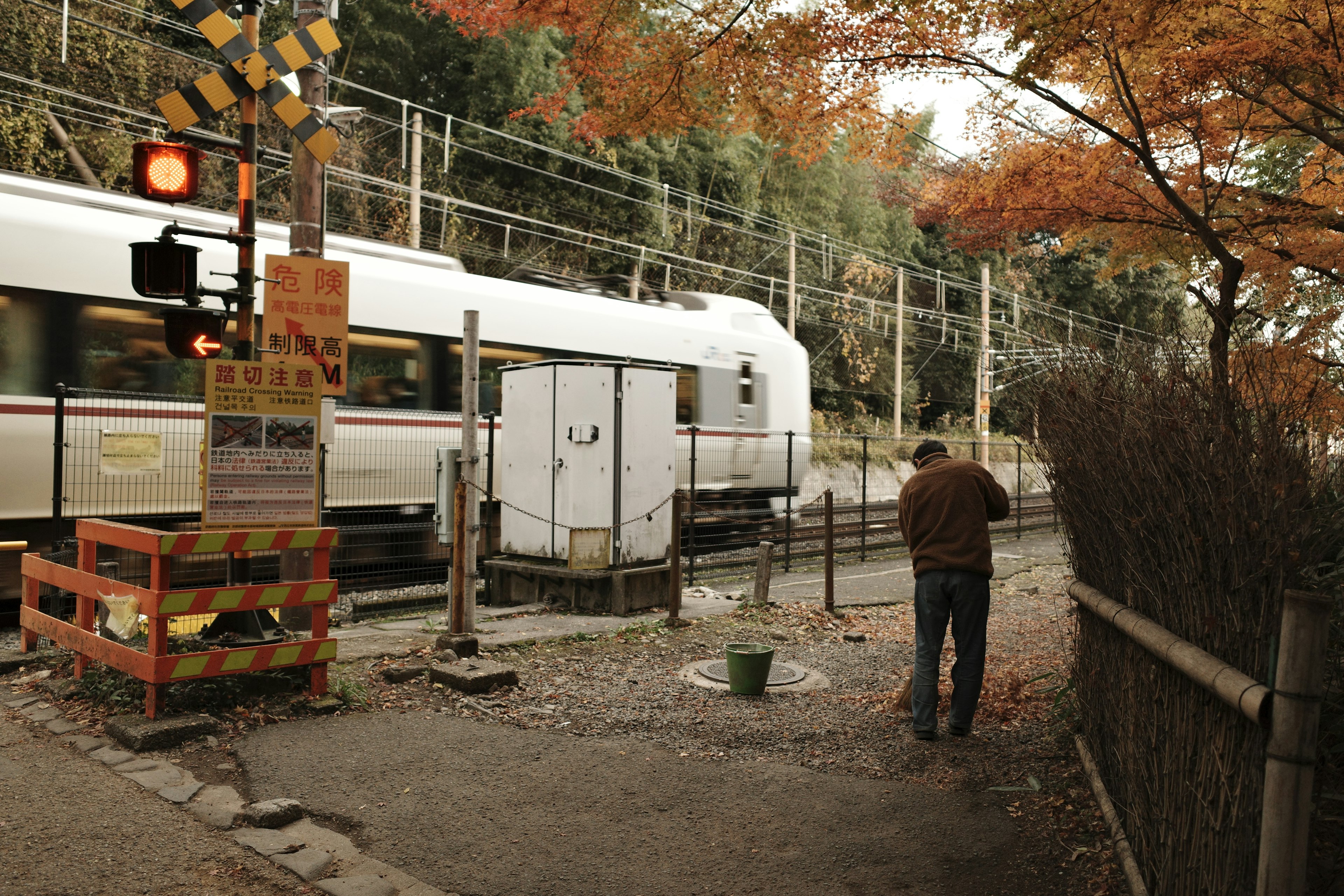 A man standing by a red signal with a passing train