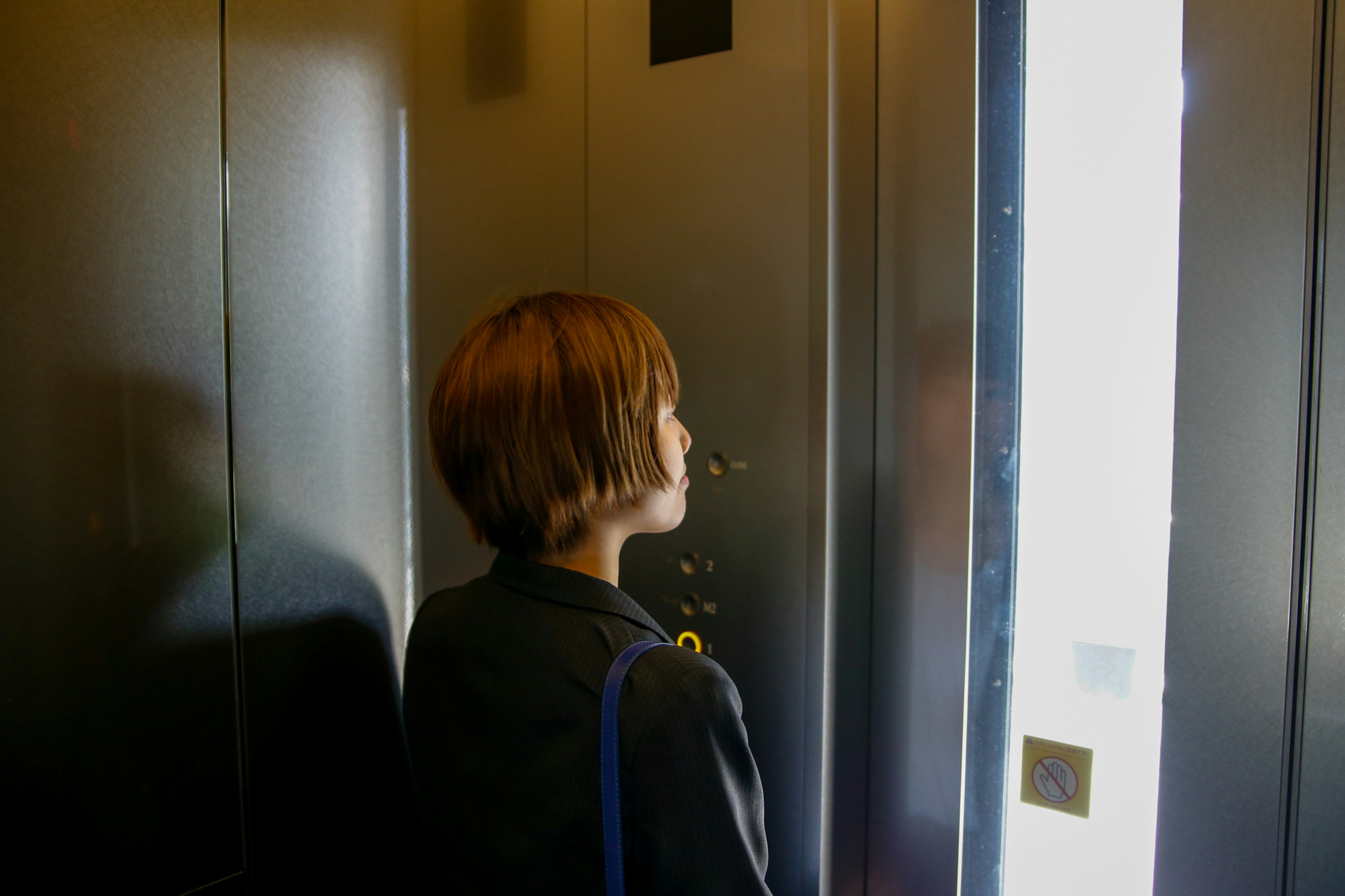 Wanita berambut pendek melihat keluar dari lift Pencahayaan lembut dan interior modern