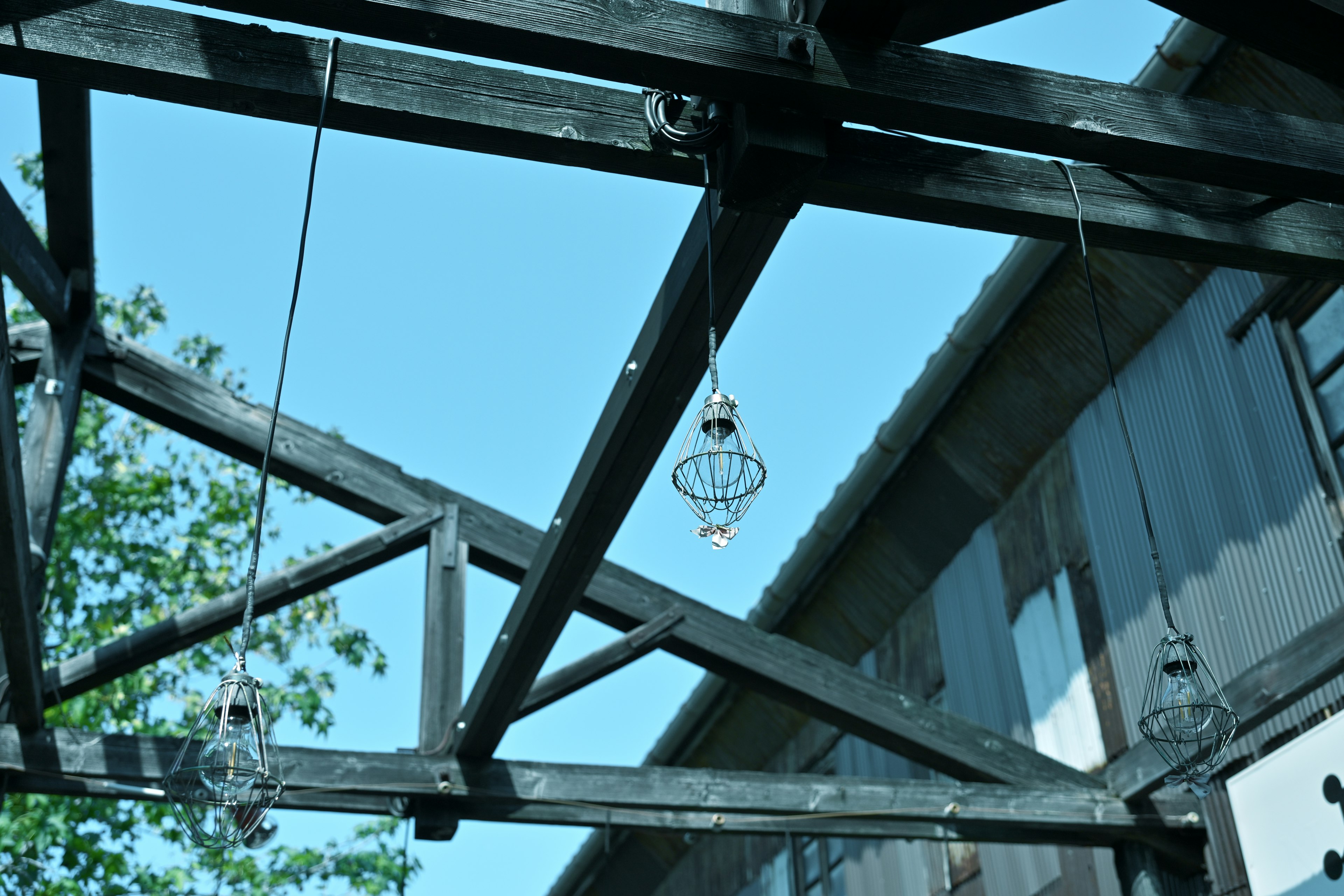 Wooden beams with hanging light fixtures under a blue sky