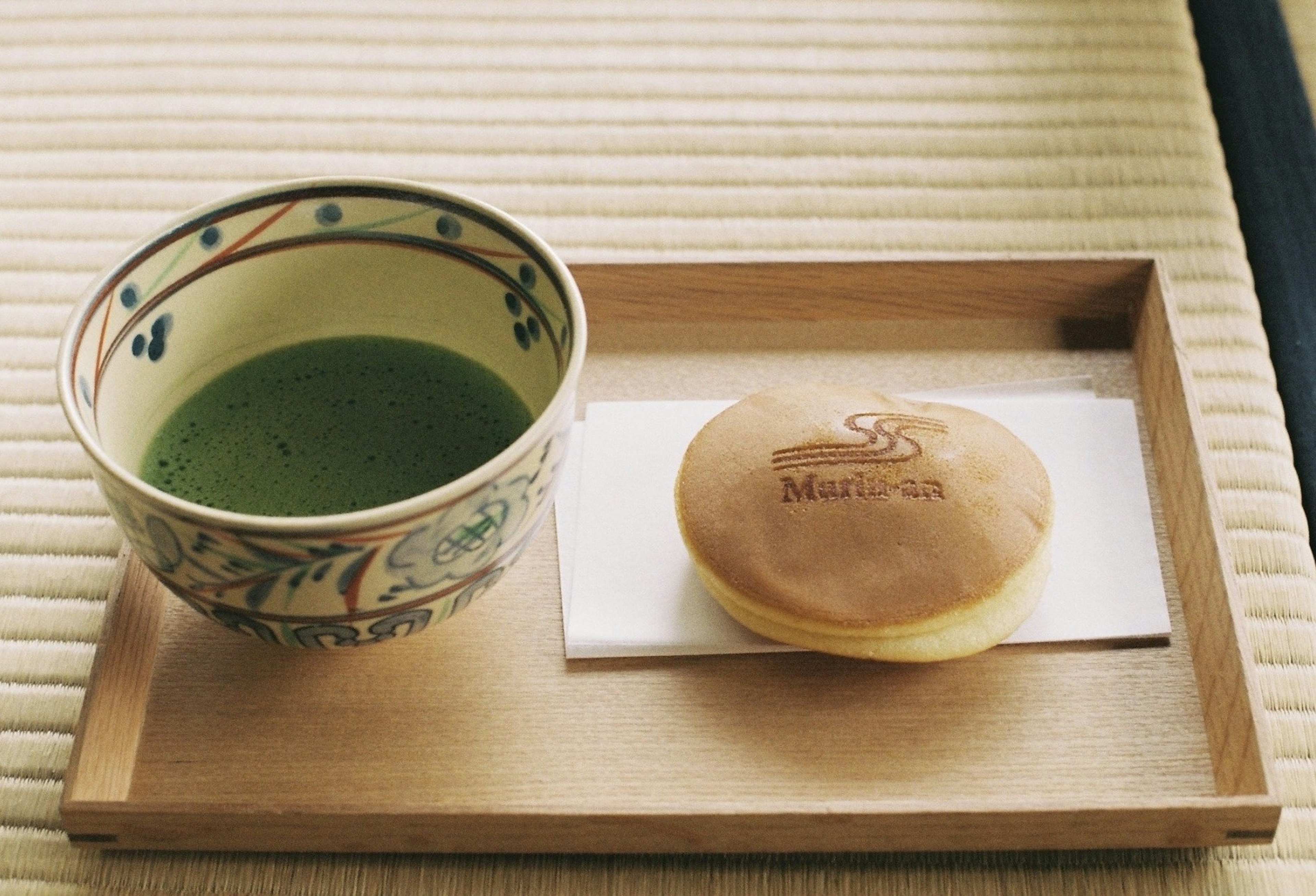 Un plateau en bois avec du thé matcha et un petit pain sucré