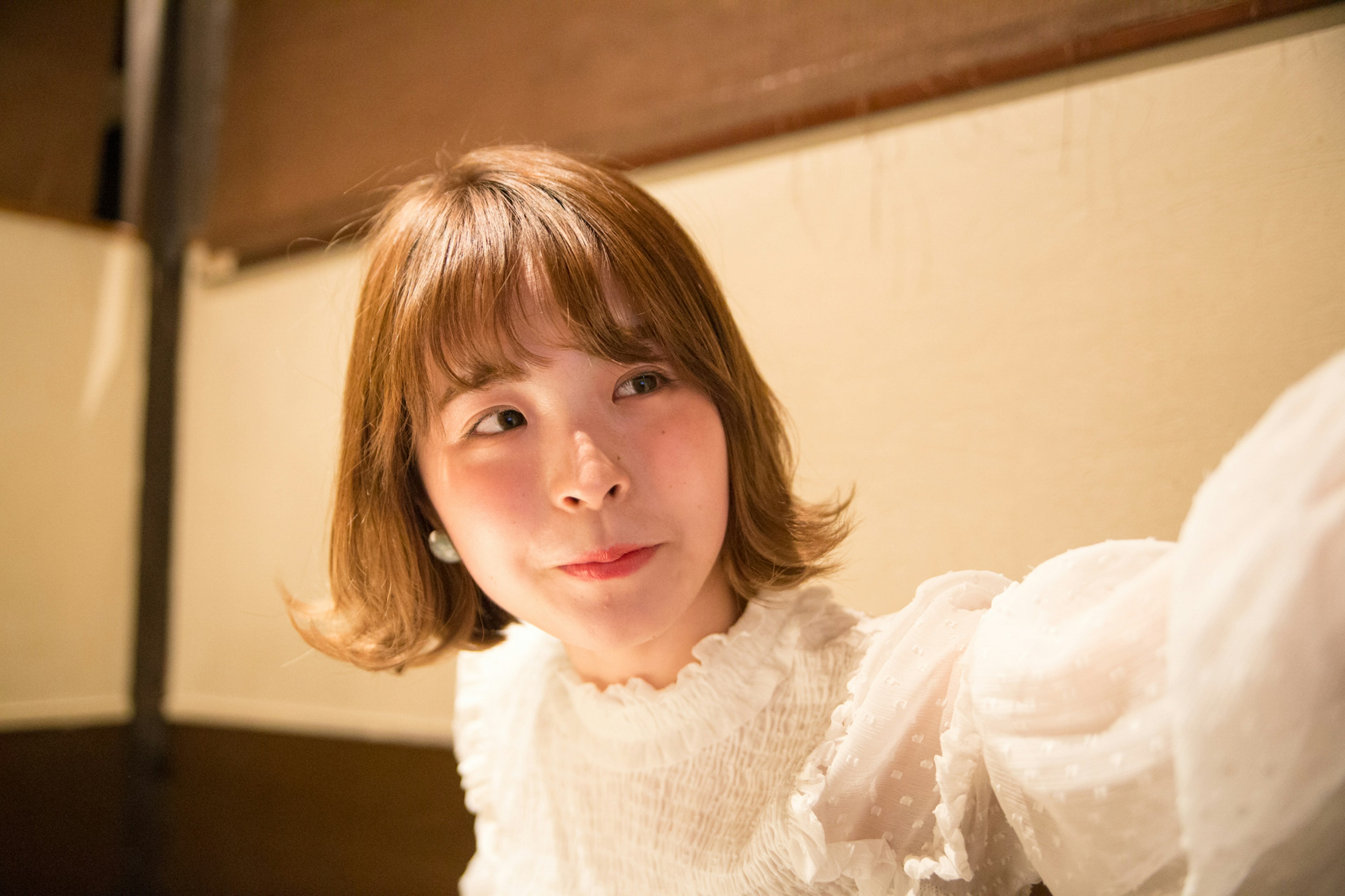 A woman smiling while wearing a white blouse