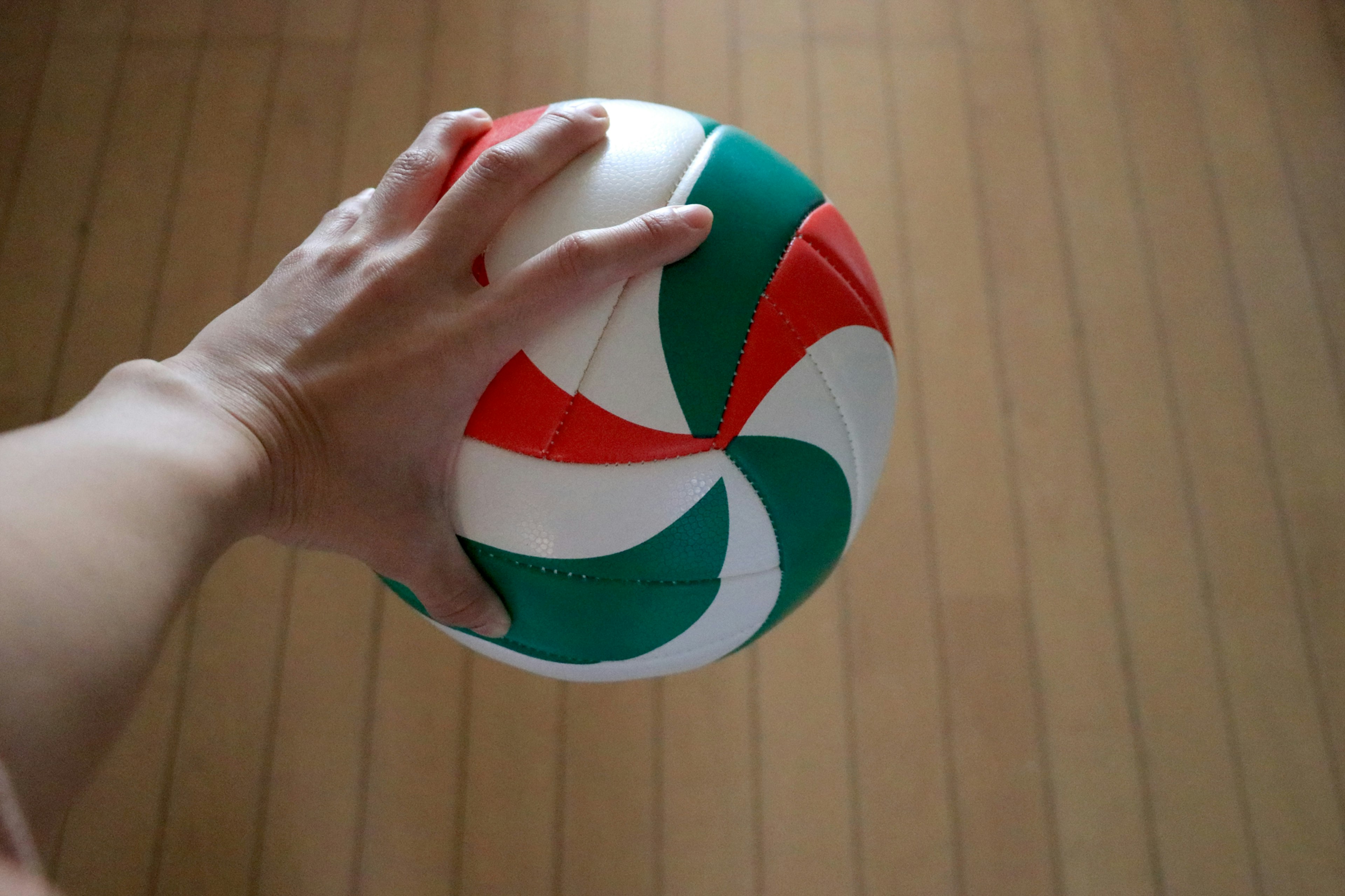 Hand holding a red and green spiral patterned ball