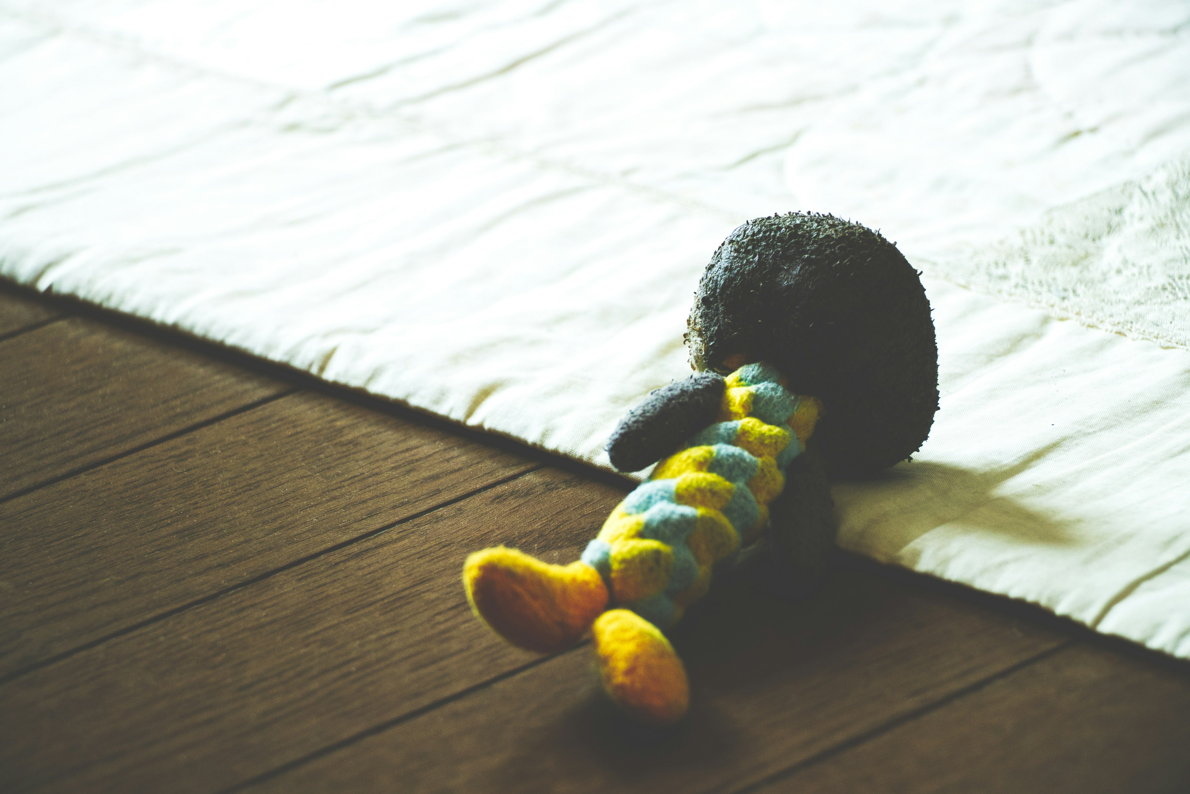 Jouet en peluche coloré couché sur une surface en tissu blanc