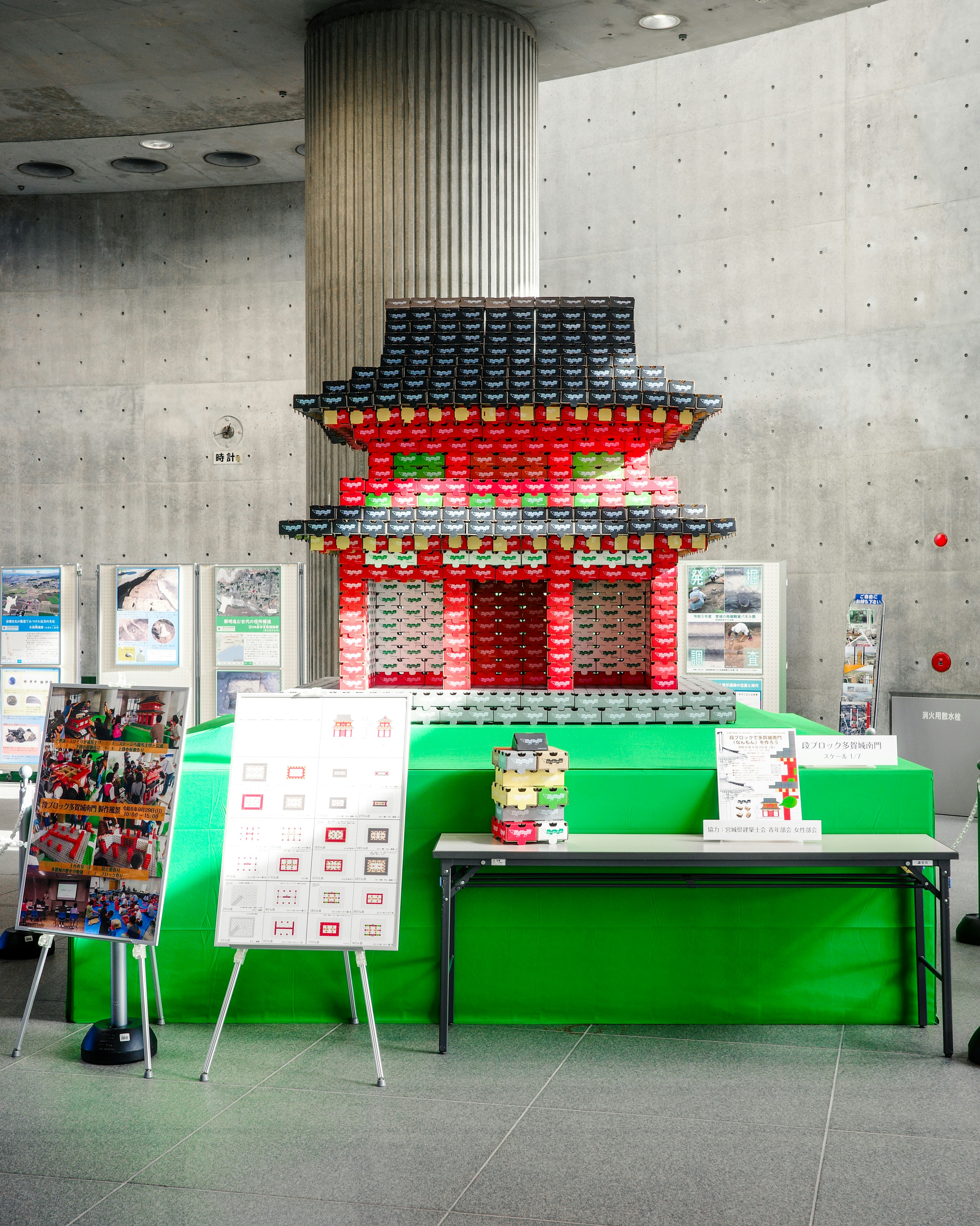 Exhibición con una réplica de edificio tradicional japonés en rojo y negro con fondo verde