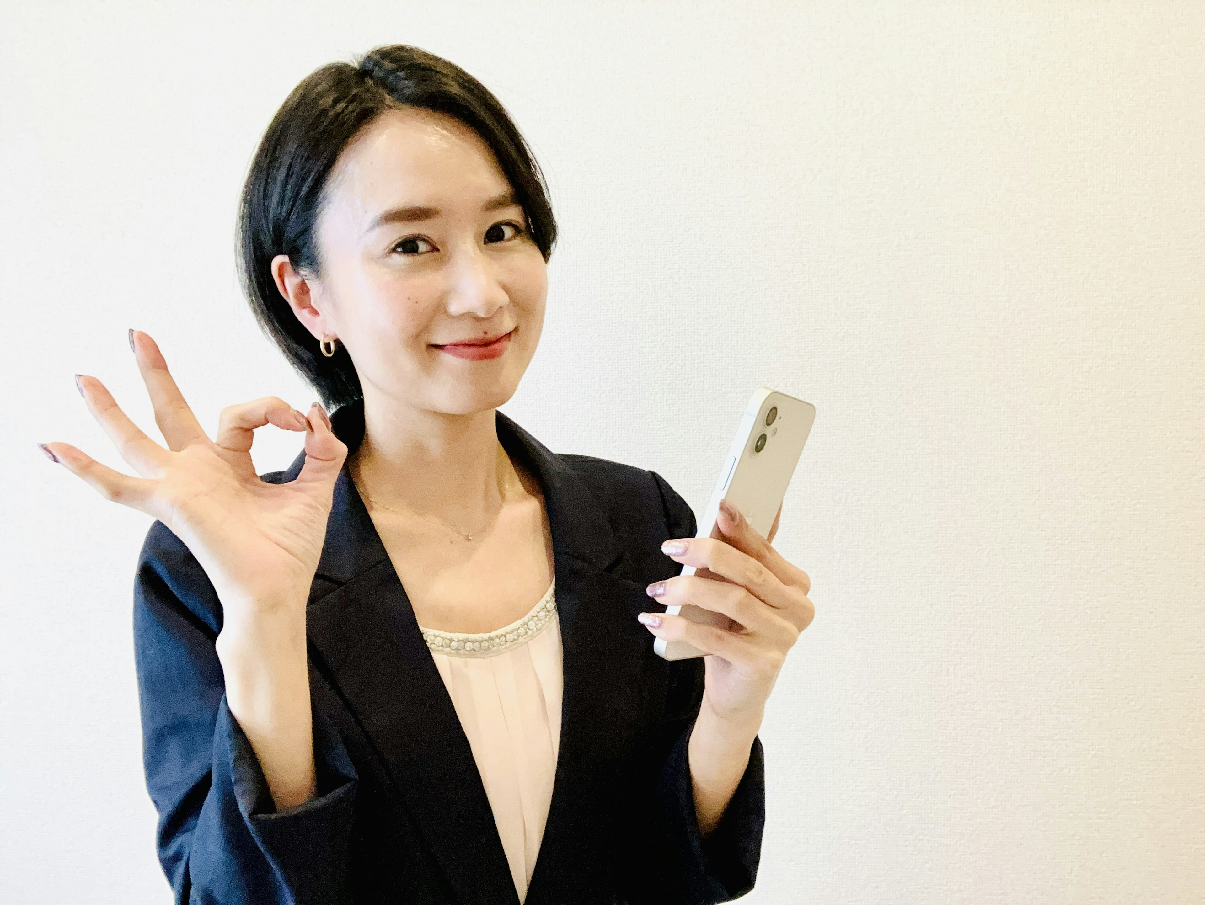 Mujer haciendo un signo de OK con la mano mientras sostiene un smartphone