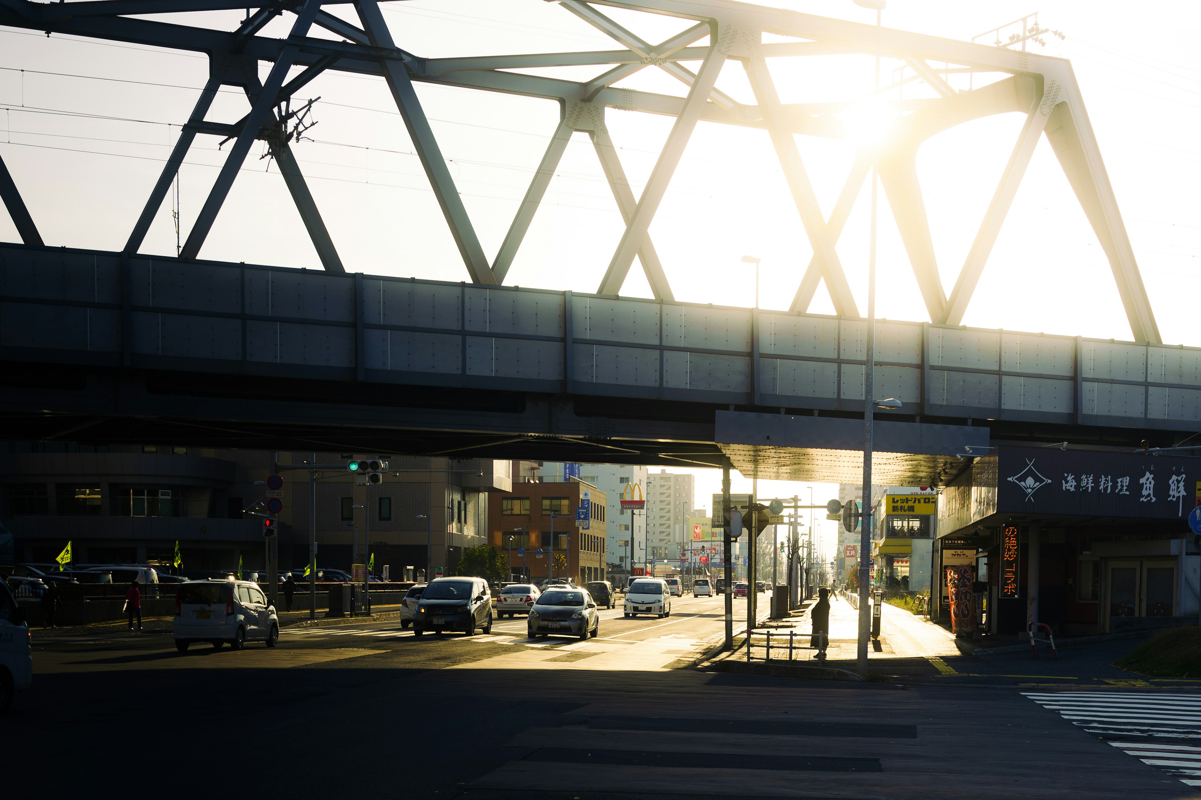 Sonnenlicht, das durch eine Eisenbahnbrücke über eine Straße mit Autos scheint