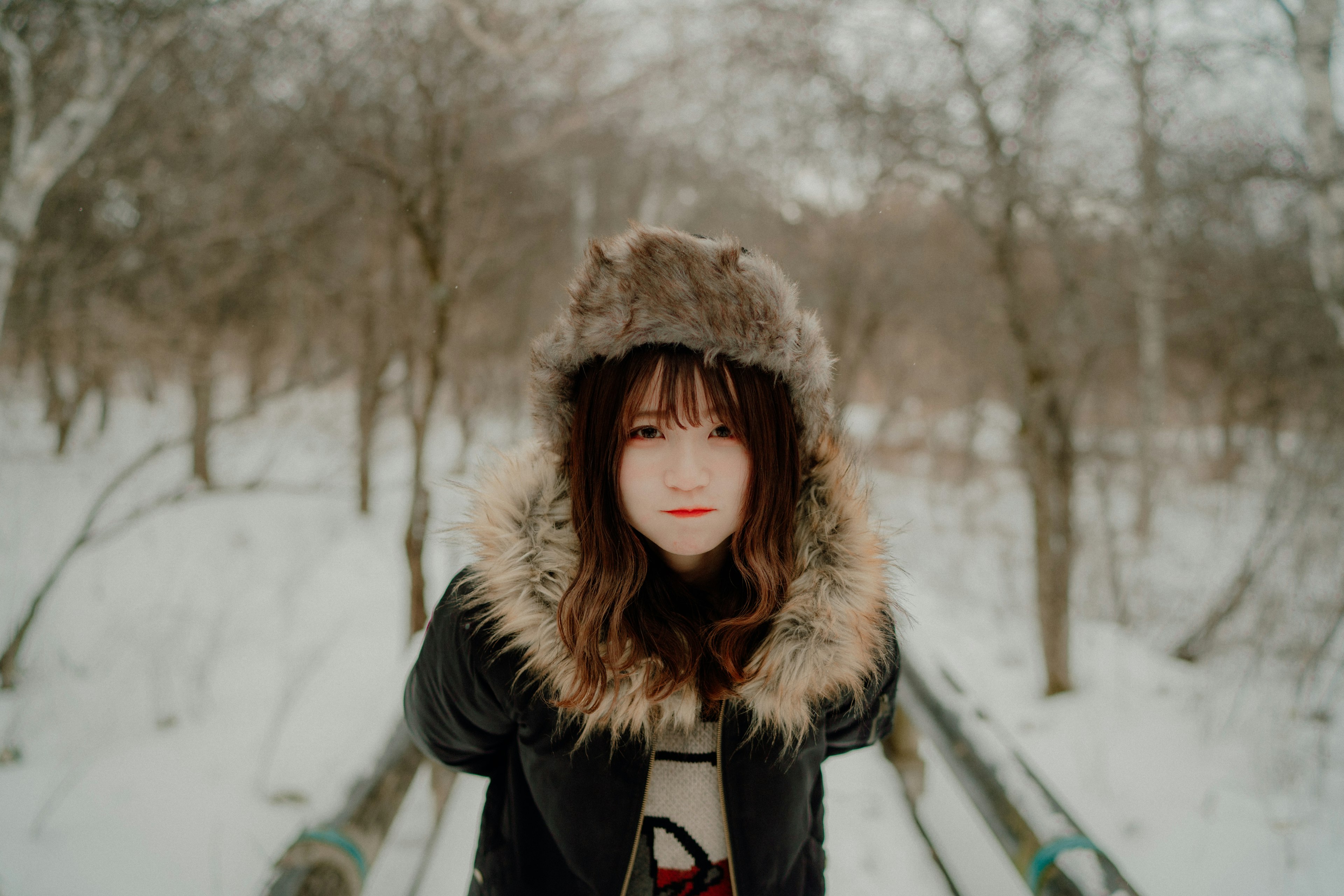 雪の中でふわふわの帽子をかぶった若い女性のポートレート