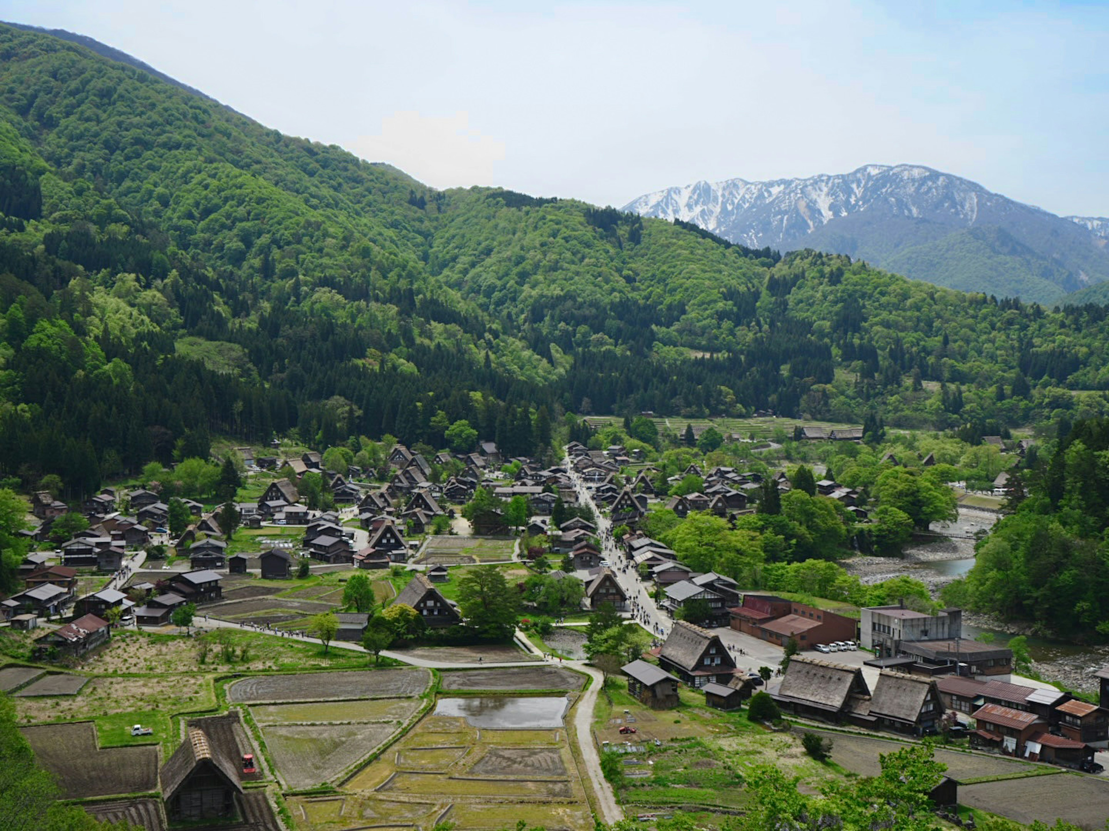 Scenic view of a traditional Japanese village surrounded by lush green mountains