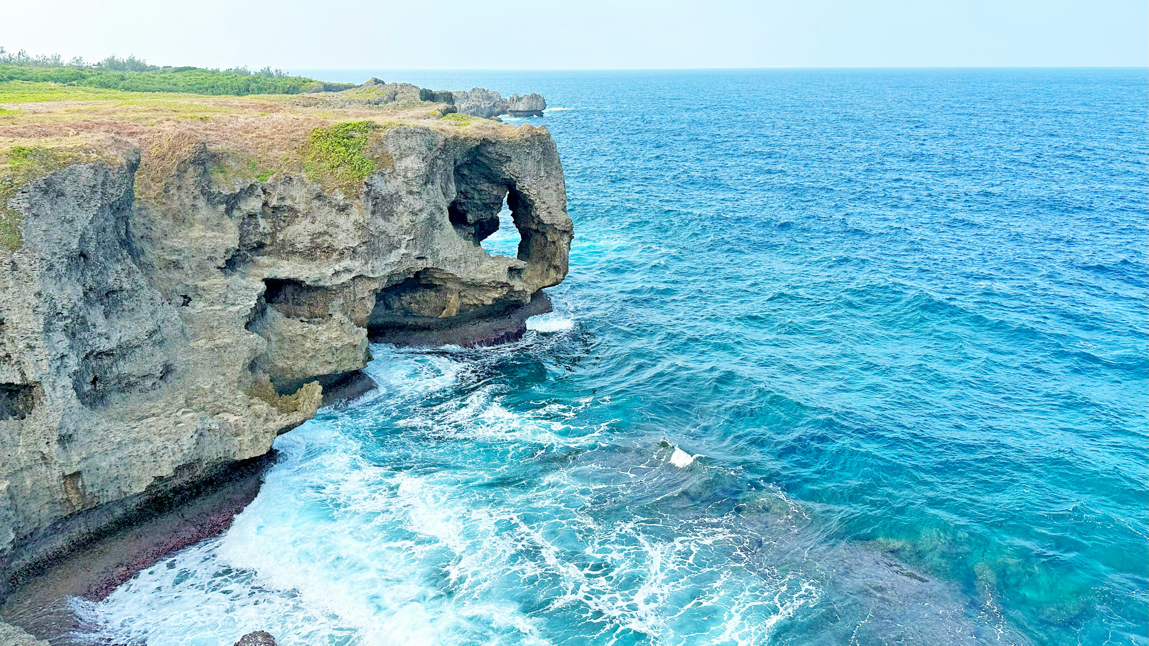 Pemandangan indah ombak laut biru menghantam tebing berbatu