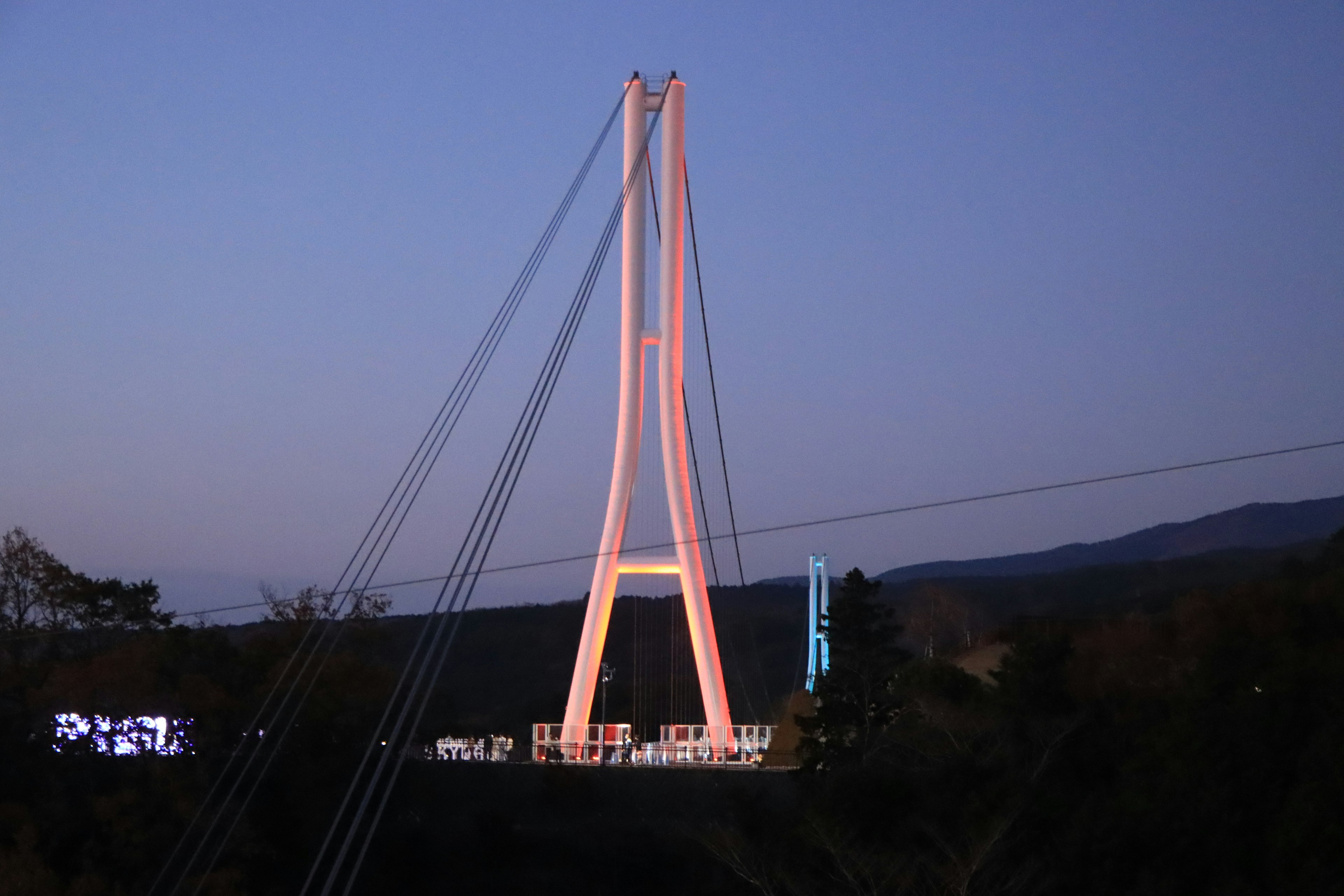 Beeindruckendes Bild einer Hängebrücke in der Dämmerung mit beleuchteten Türmen und Kabeln