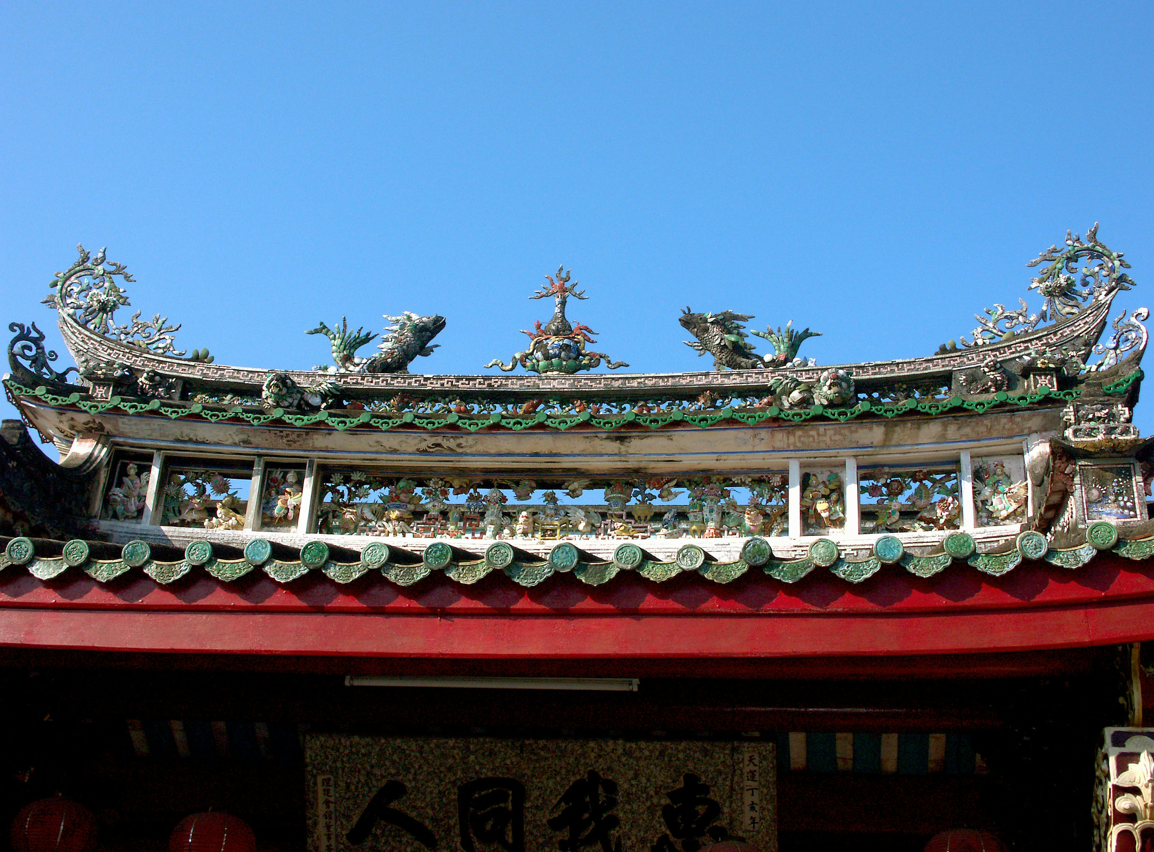 Dach eines chinesischen Tempels unter blauem Himmel mit dekorativen Drachen und aufwendigen Fliesen