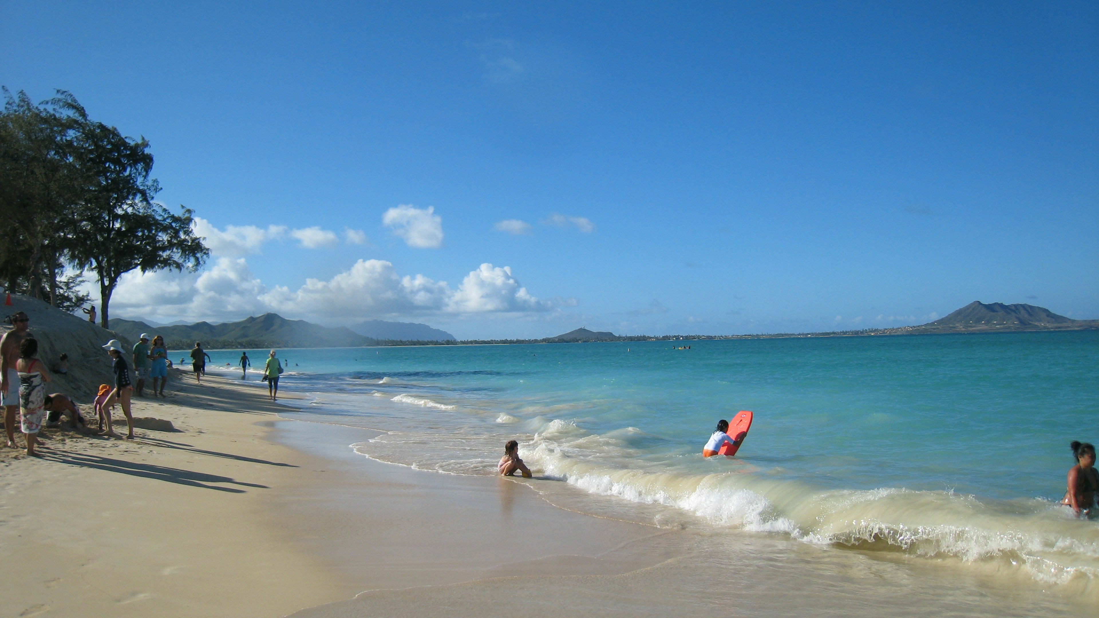 People enjoying a beautiful beach with blue sky and ocean scenery