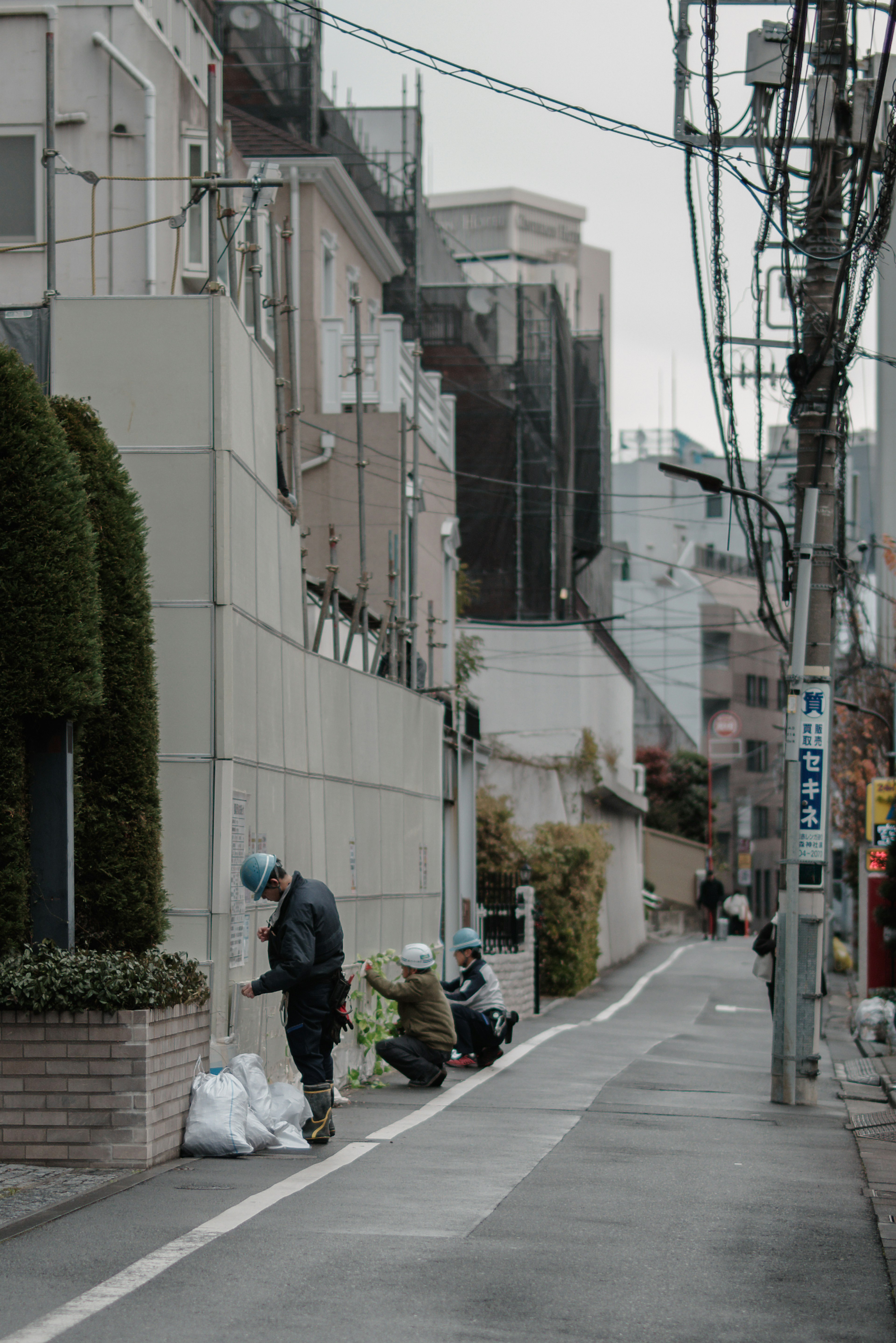 Escena de calle tranquila en Japón con personas clasificando basura y un callejón estrecho