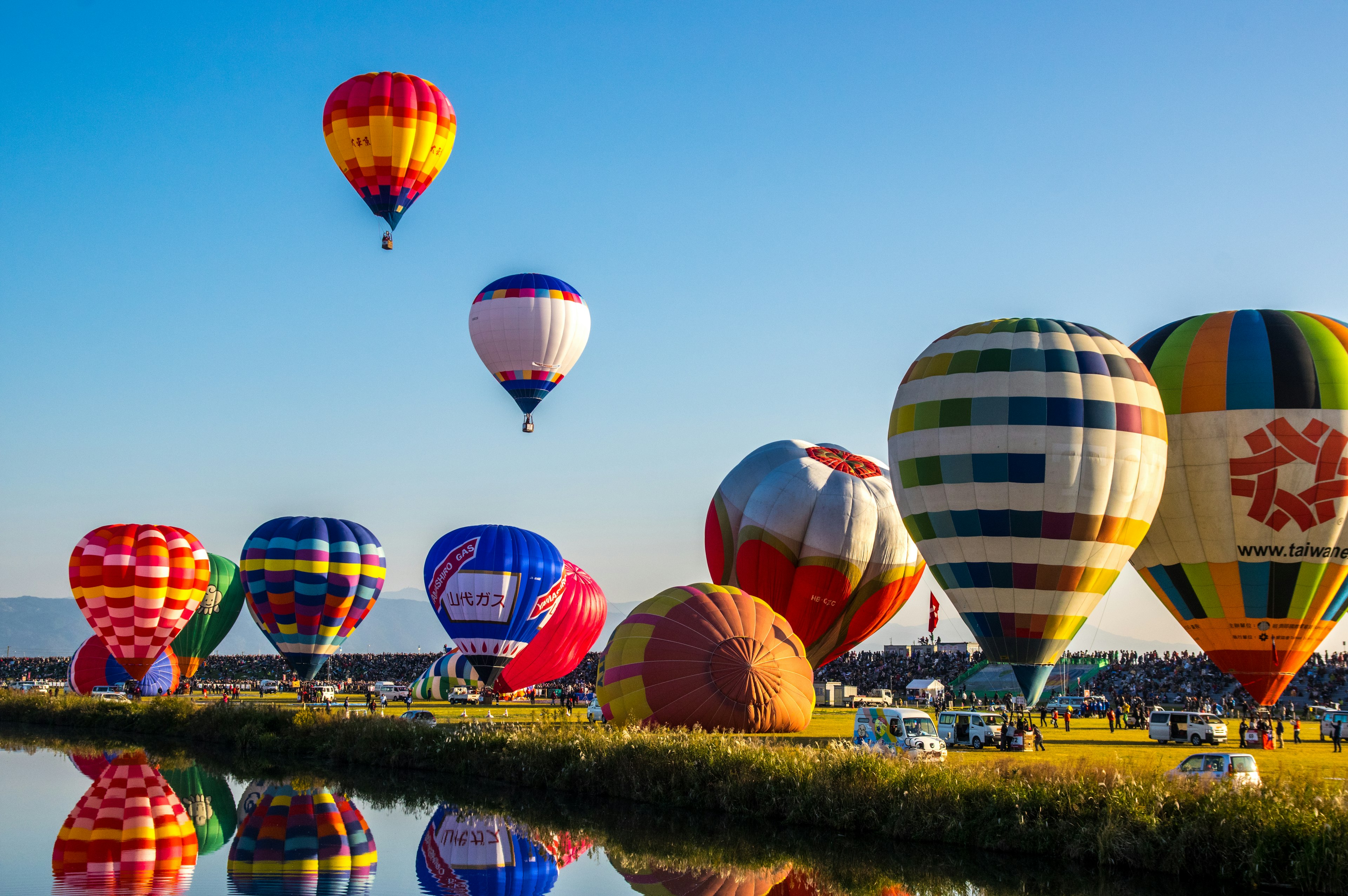 Palloni aerostatici colorati che fluttuano nel cielo con riflessi sull'acqua