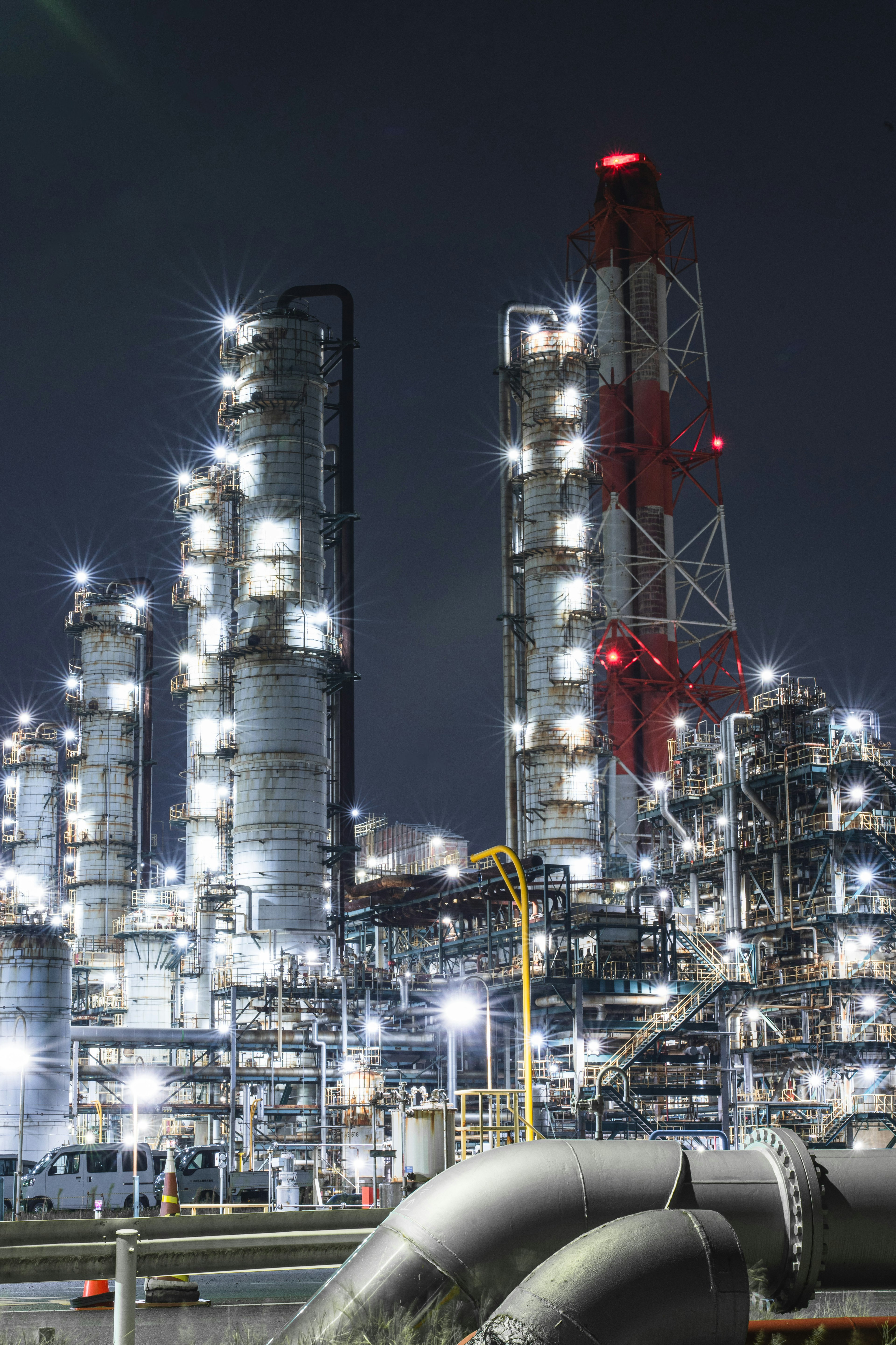 Usine industrielle illuminée la nuit avec de grandes cheminées