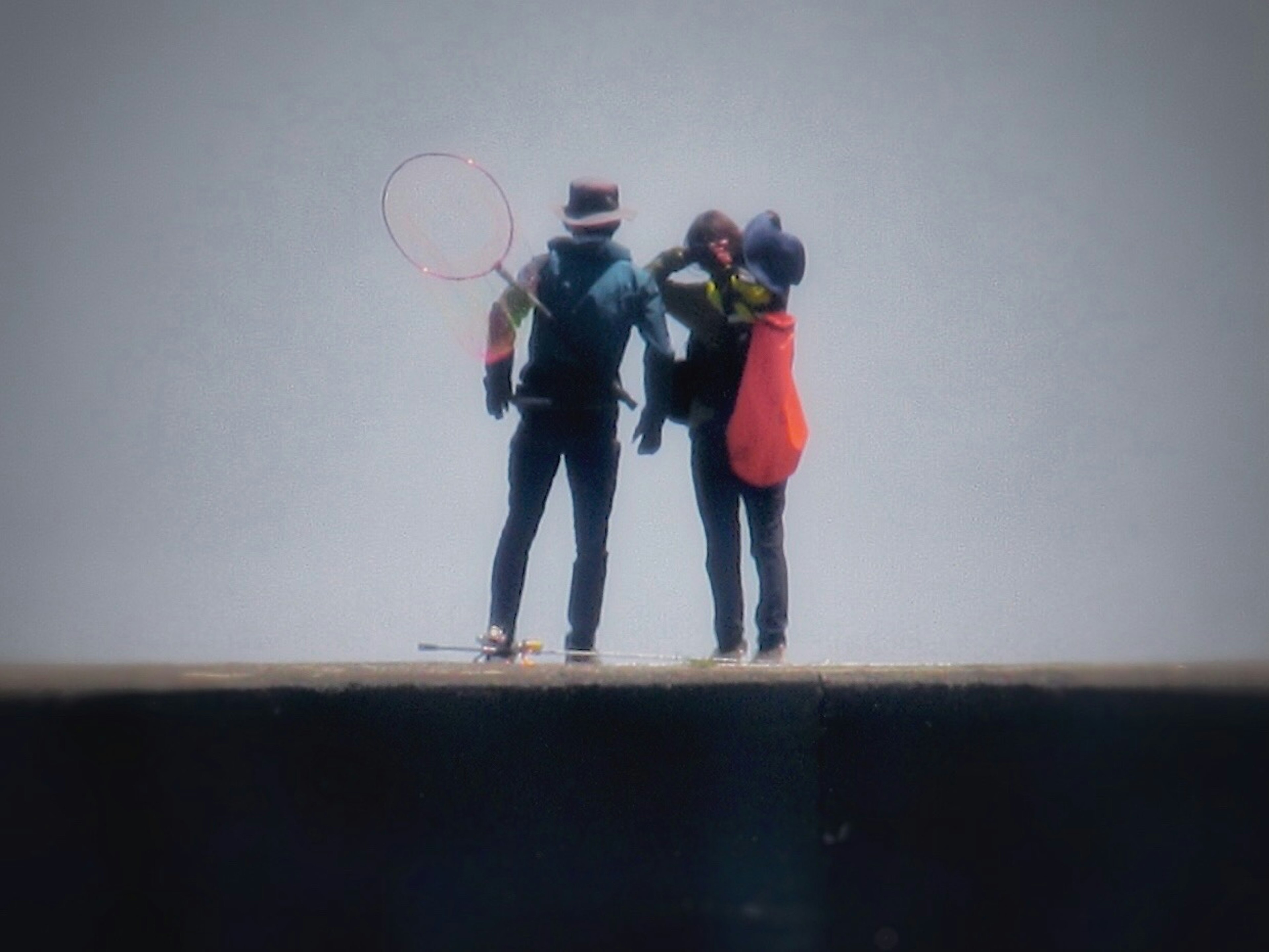 Zwei Personen stehen auf einem Pier Eine Person hält ein Netz Die andere trägt ein Kind